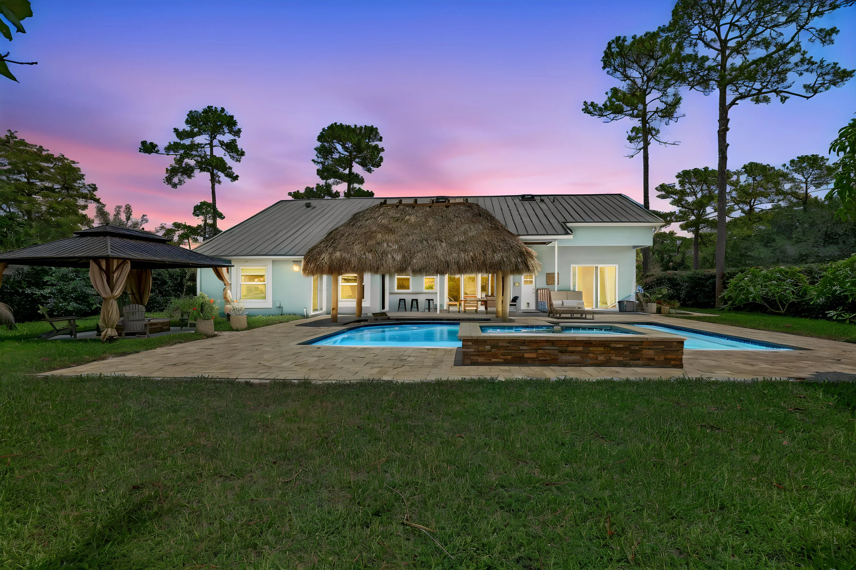 Backyard oasis featuring a swimming pool, integrated spa with stone surround, and a thatched-roof cabana