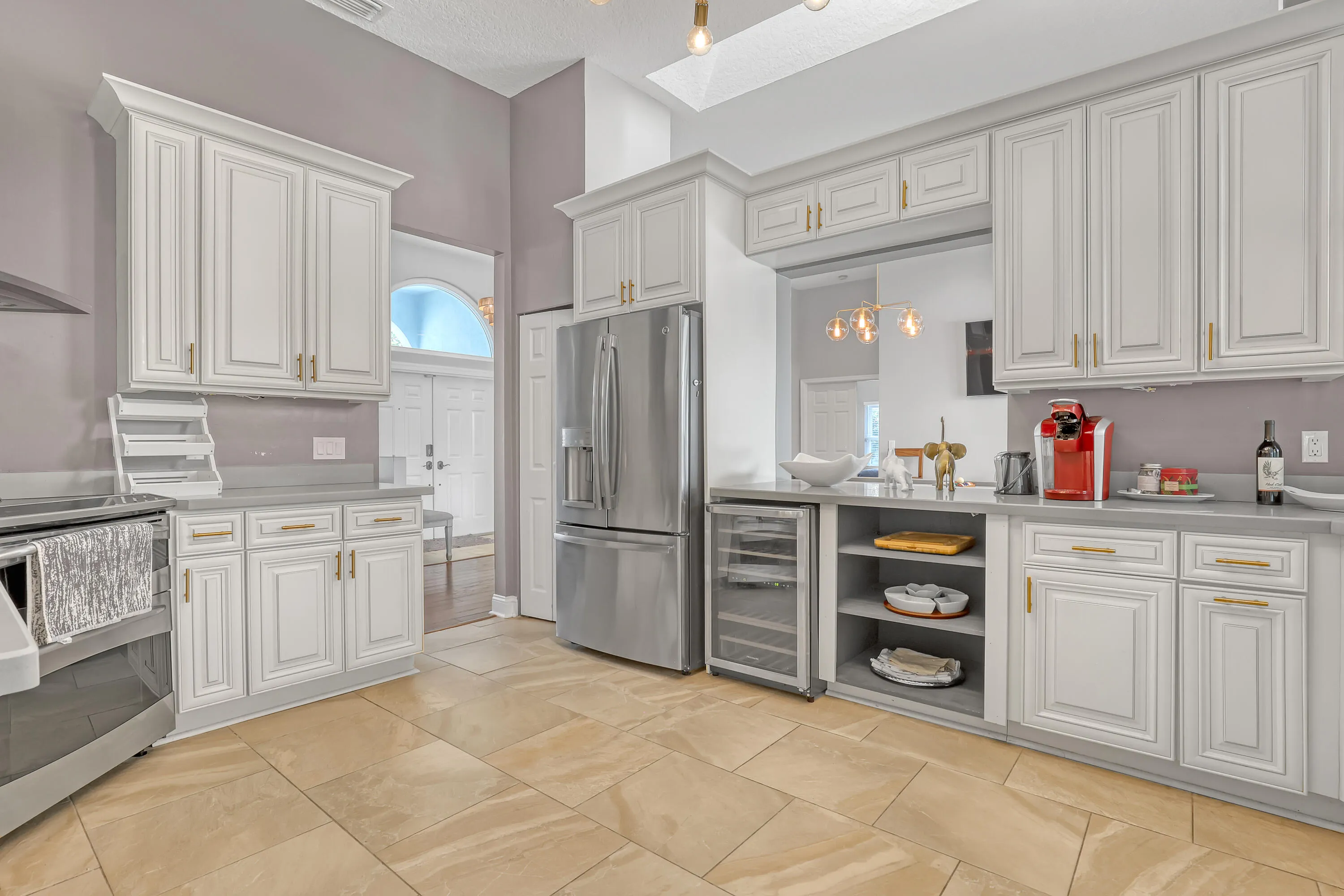 Gourmet kitchen featuring light cabinetry, stainless steel appliances, a built-in wine cooler, a large pantry, and stone-finish flooring
