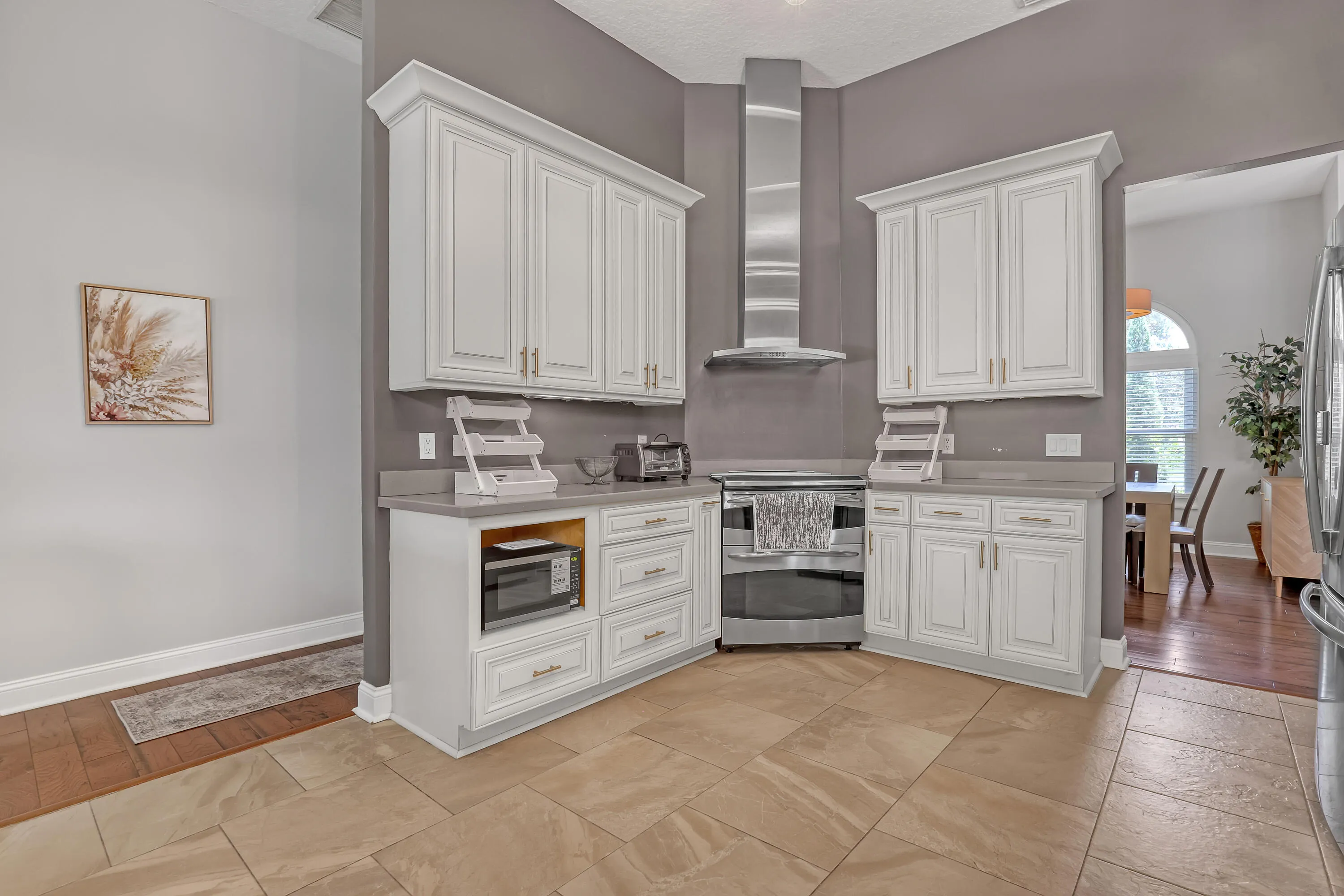 Kitchen featuring white cabinetry with gold-tone hardware, a stainless steel range hood, and a built-in stainless steel oven