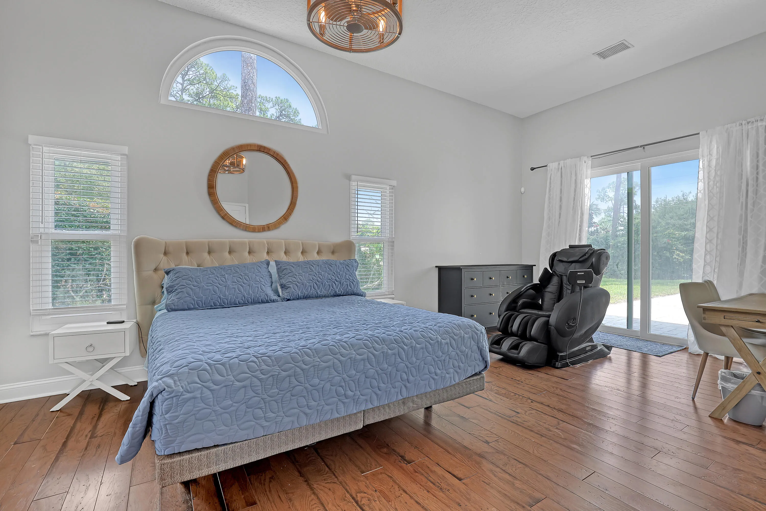 Primary Bedroom featuring vaulted ceilings, an arched transom window, and wood-finish flooring plus views of the pool