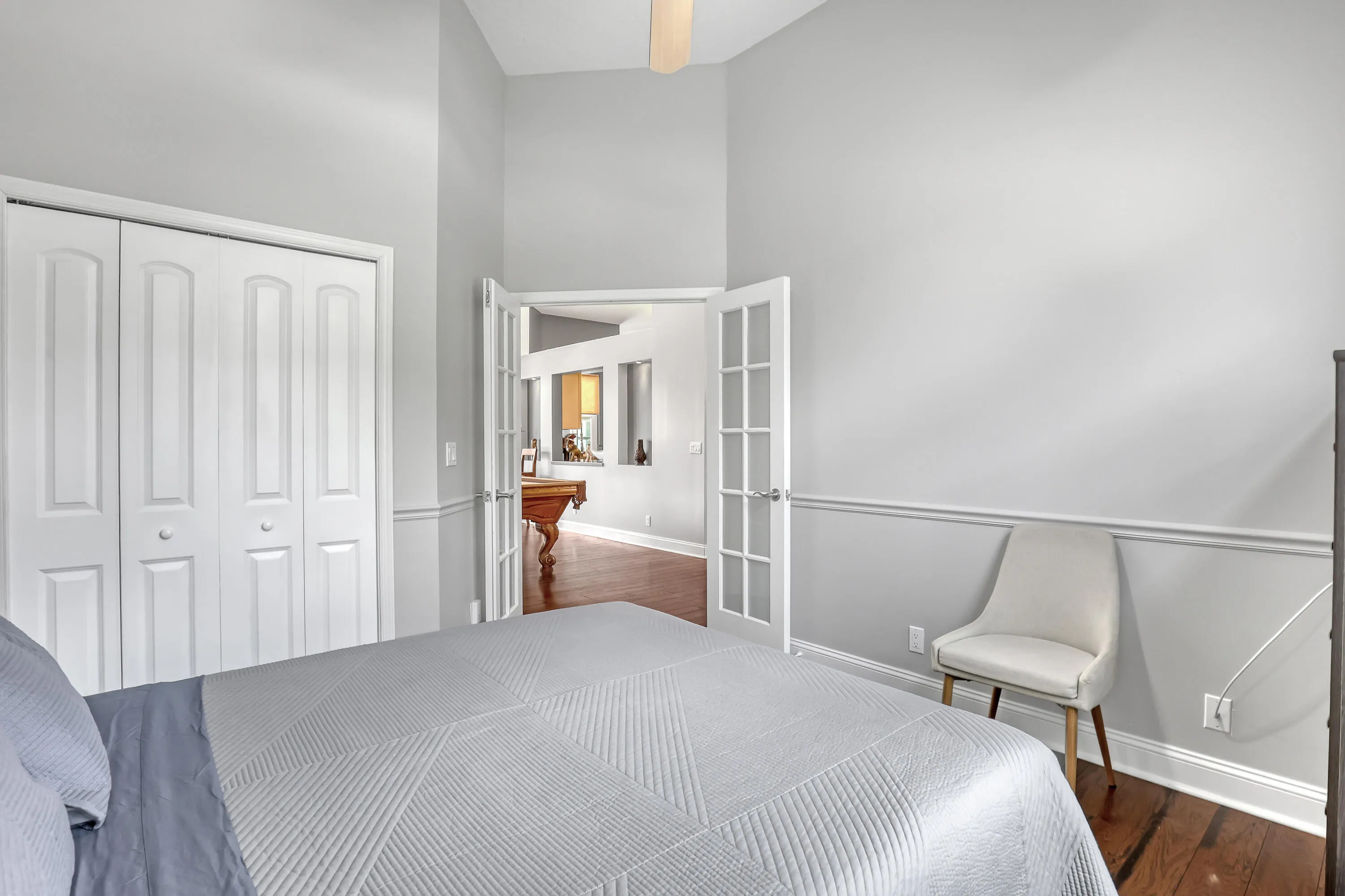 Interior room featuring light gray walls with chair rail molding, dark wood-finish flooring, and white bi-fold closet doors