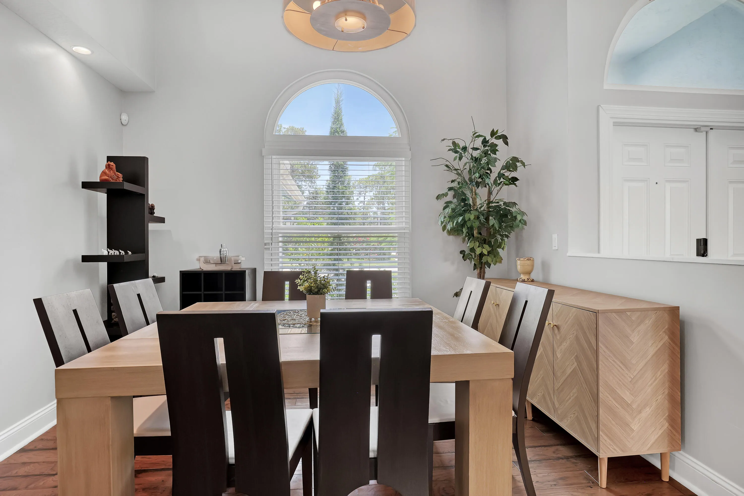 Dining area featuring soaring ceilings, a large arched window with blinds, recessed lighting, and rich wood-finish flooring