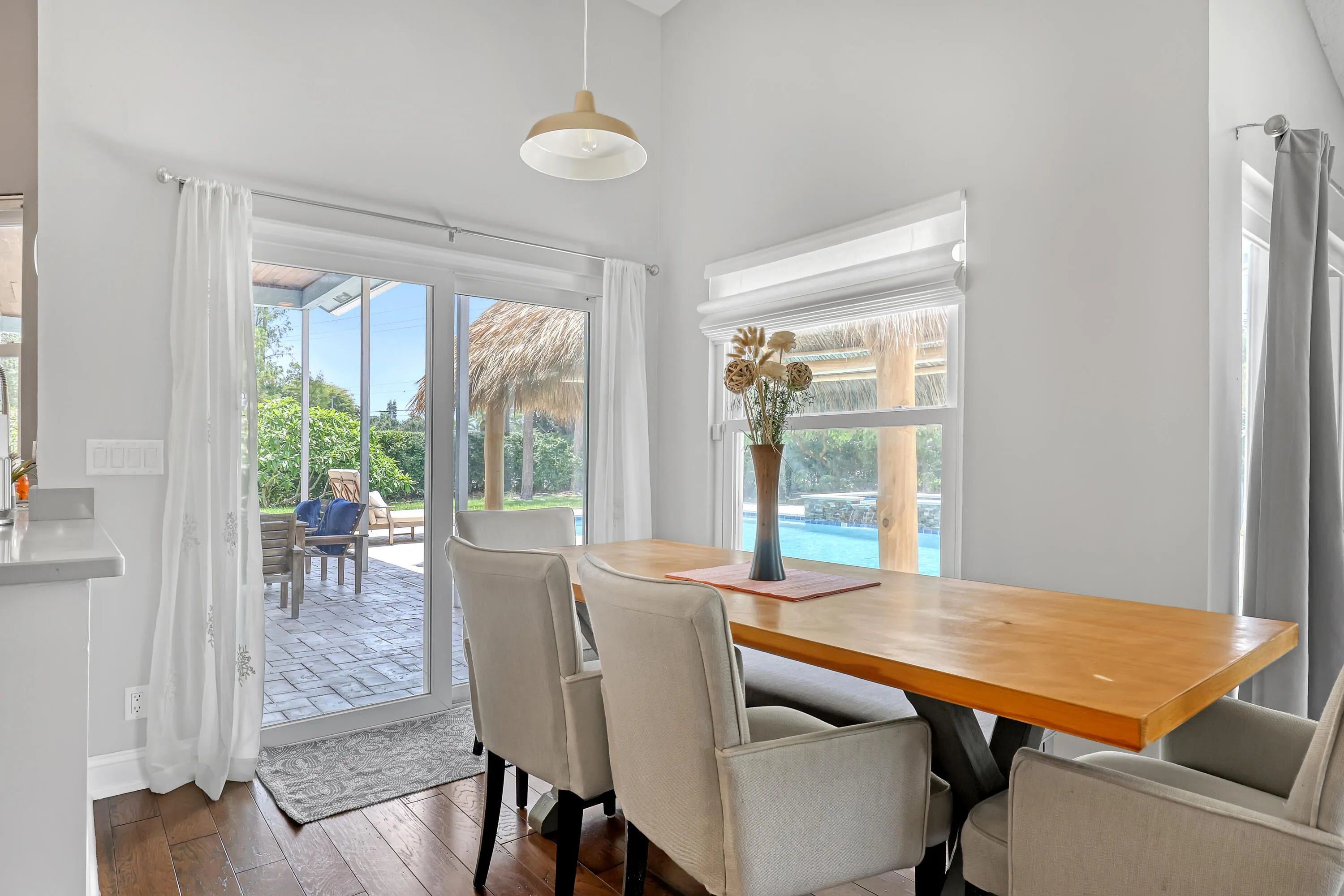 Breakfast area with wood-finish flooring, a contemporary pendant light fixture, and a large window for great pool views