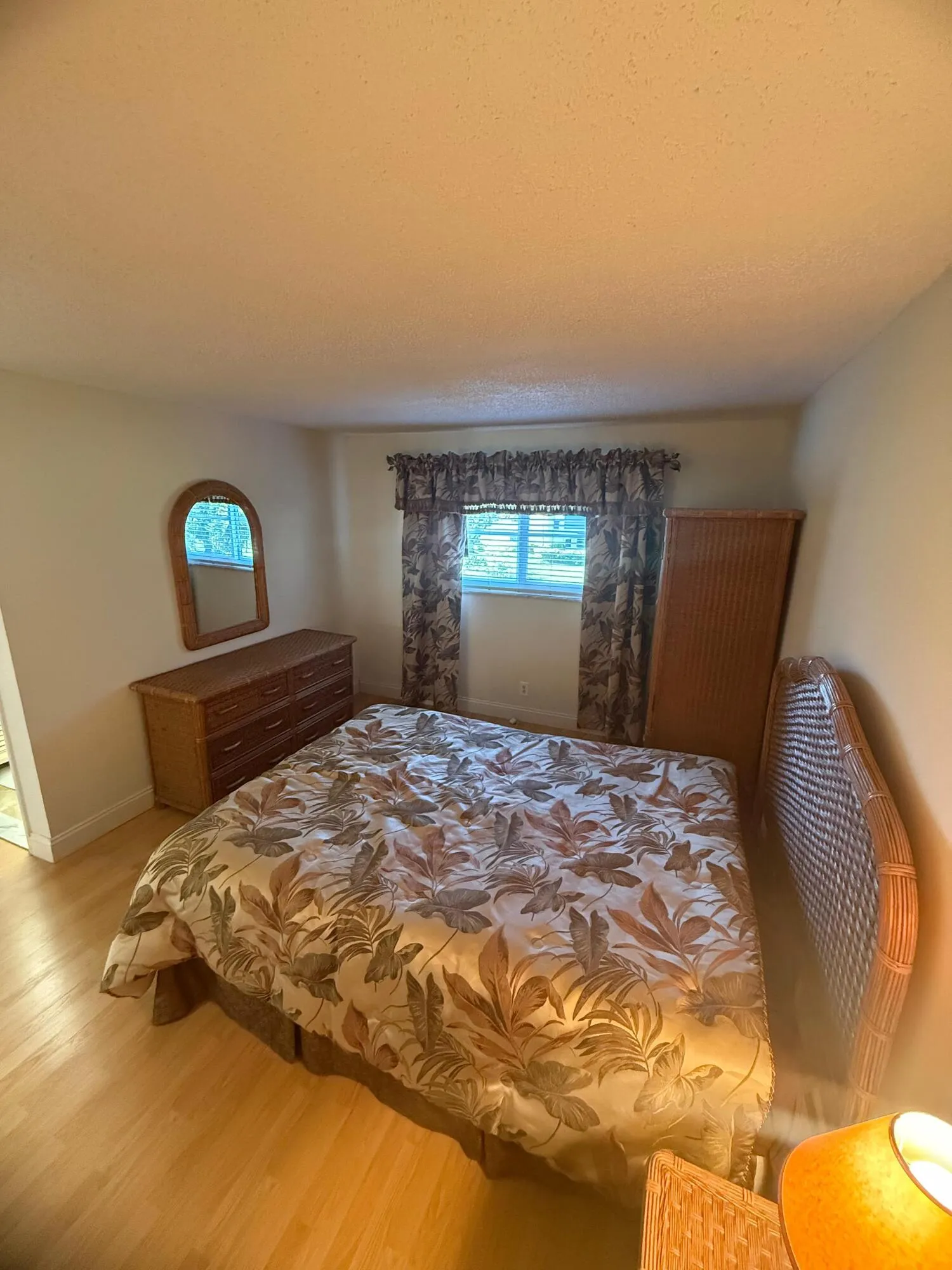 Spacious room featuring wood-finish flooring, a window with horizontal blinds, and neutral-toned walls