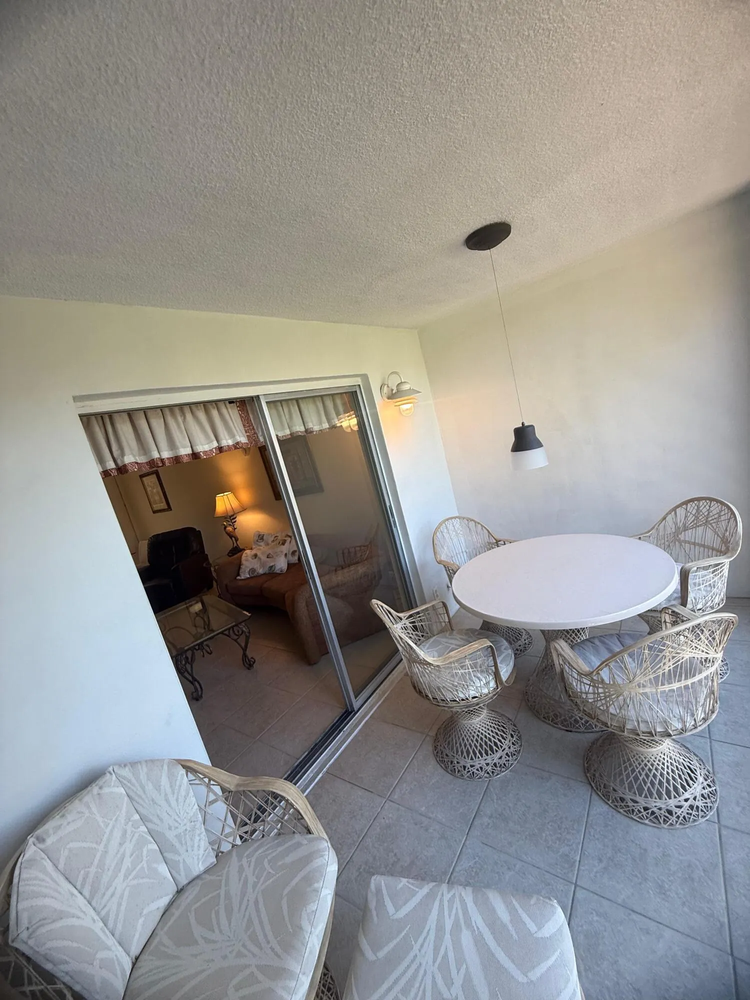 Tiled outdoor patio with a modern pendant light fixture and an exterior wall sconce