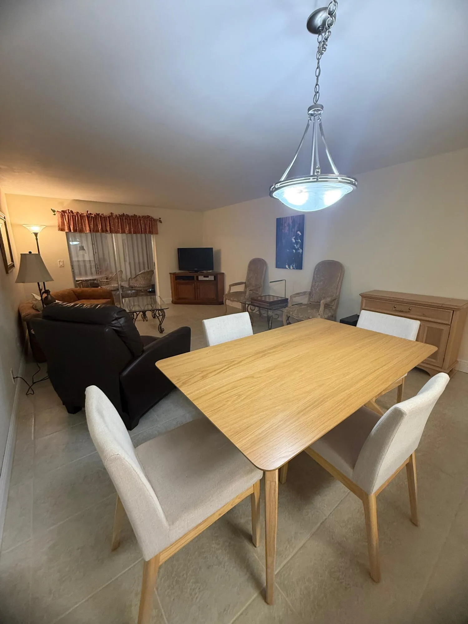 Open-concept living area featuring a dining space with a light wood-finish table and four upholstered chairs
