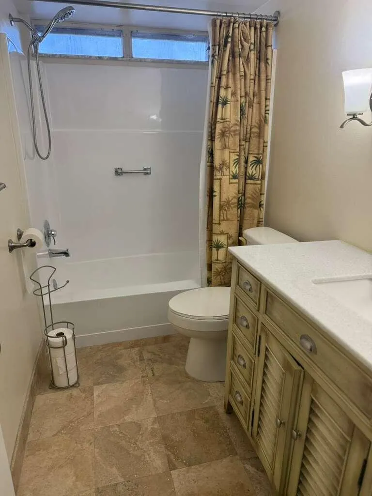 Bathroom featuring a single vanity with a solid surface countertop, integrated sink, and shutter-style cabinetry