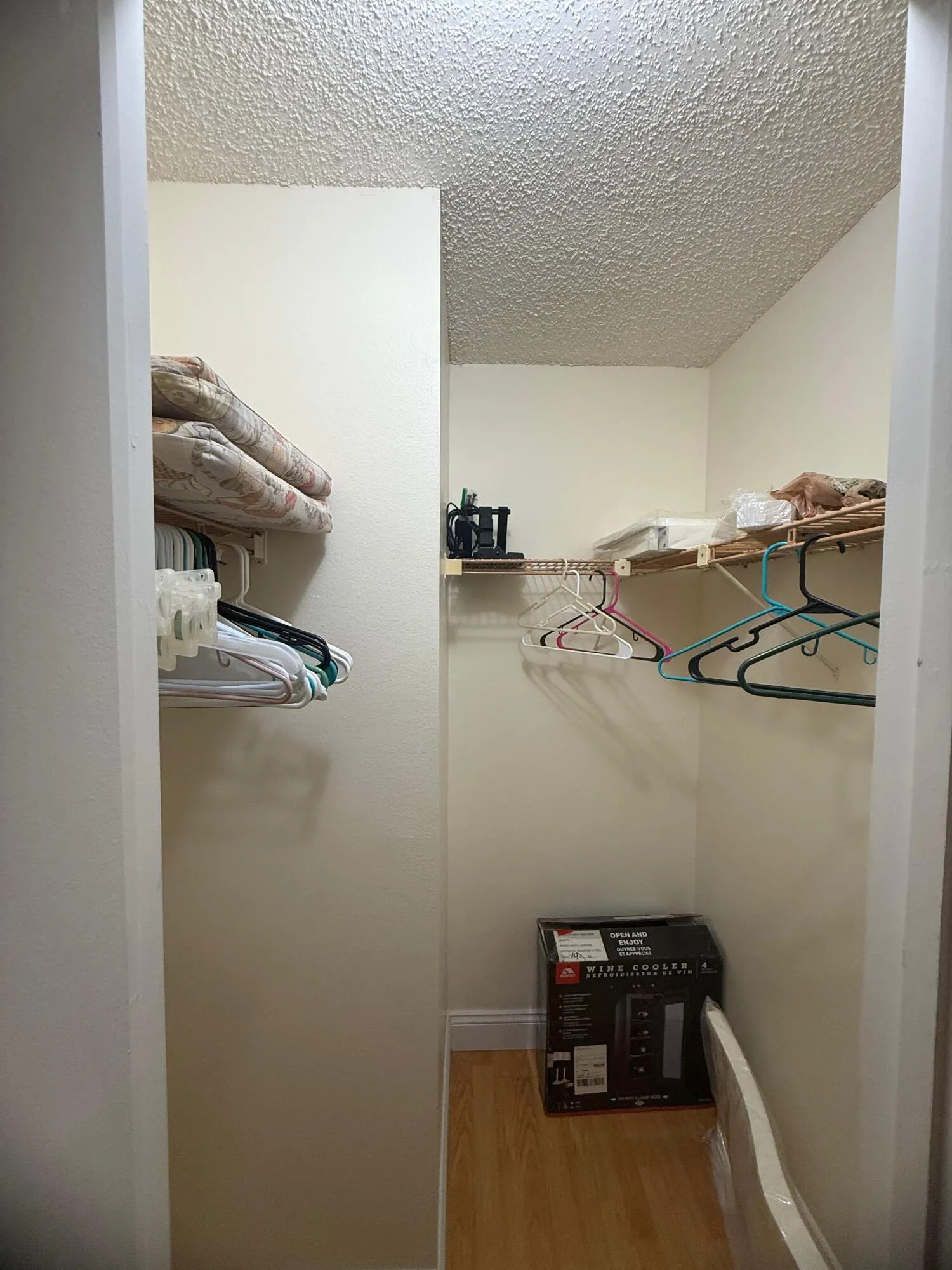 Walk-in closet featuring light wood-finish flooring, white baseboards, and built-in shelving and hanging rods