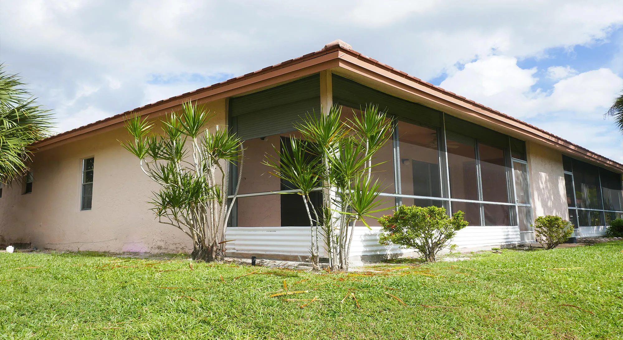 Exterior stucco residence featuring a tiled roof and a screened-in lanai