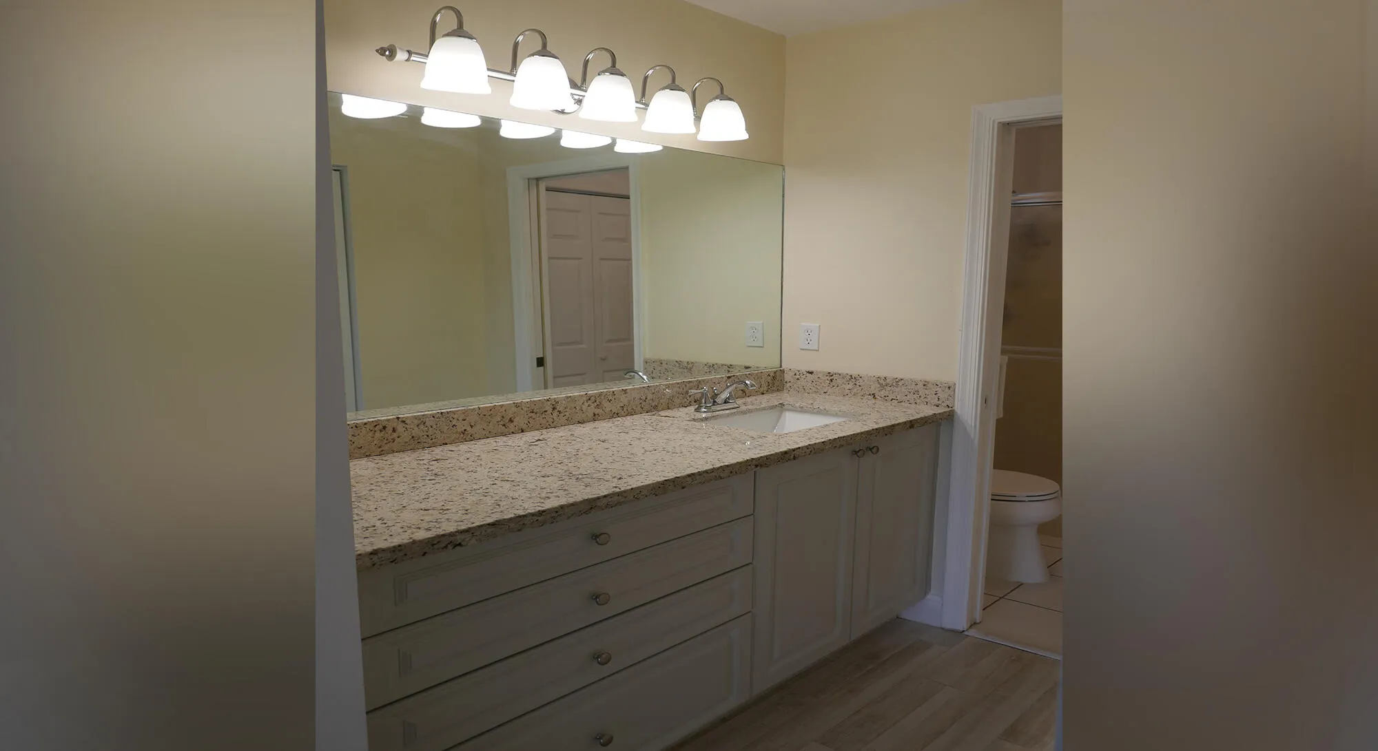 Bathroom vanity featuring a speckled countertop, integrated sink, and brushed nickel faucet