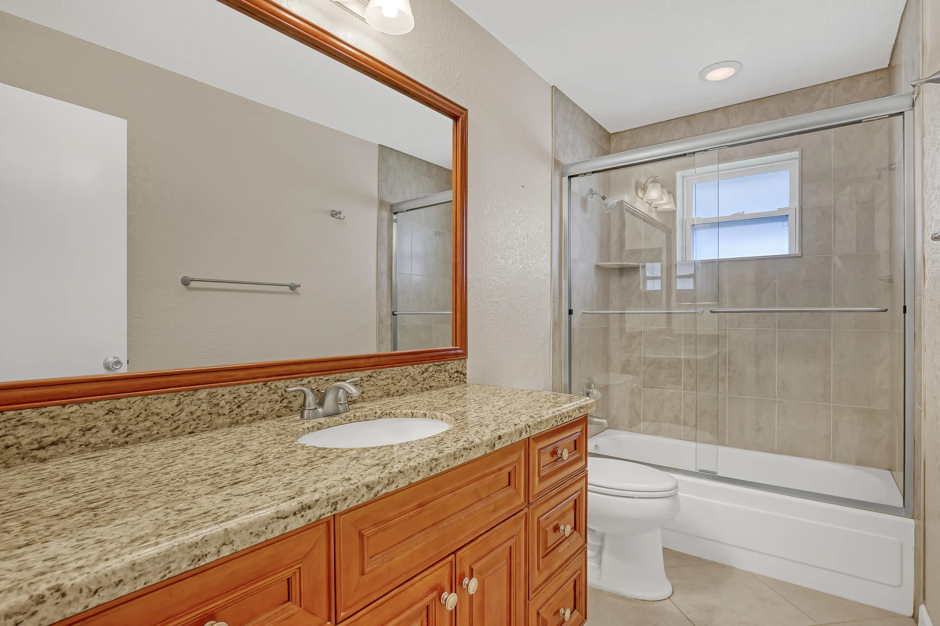 Guest bathroom with new vanity, granite countertop, recessed lighting in glass enclosed tub/shower. Updated electrical fixture.