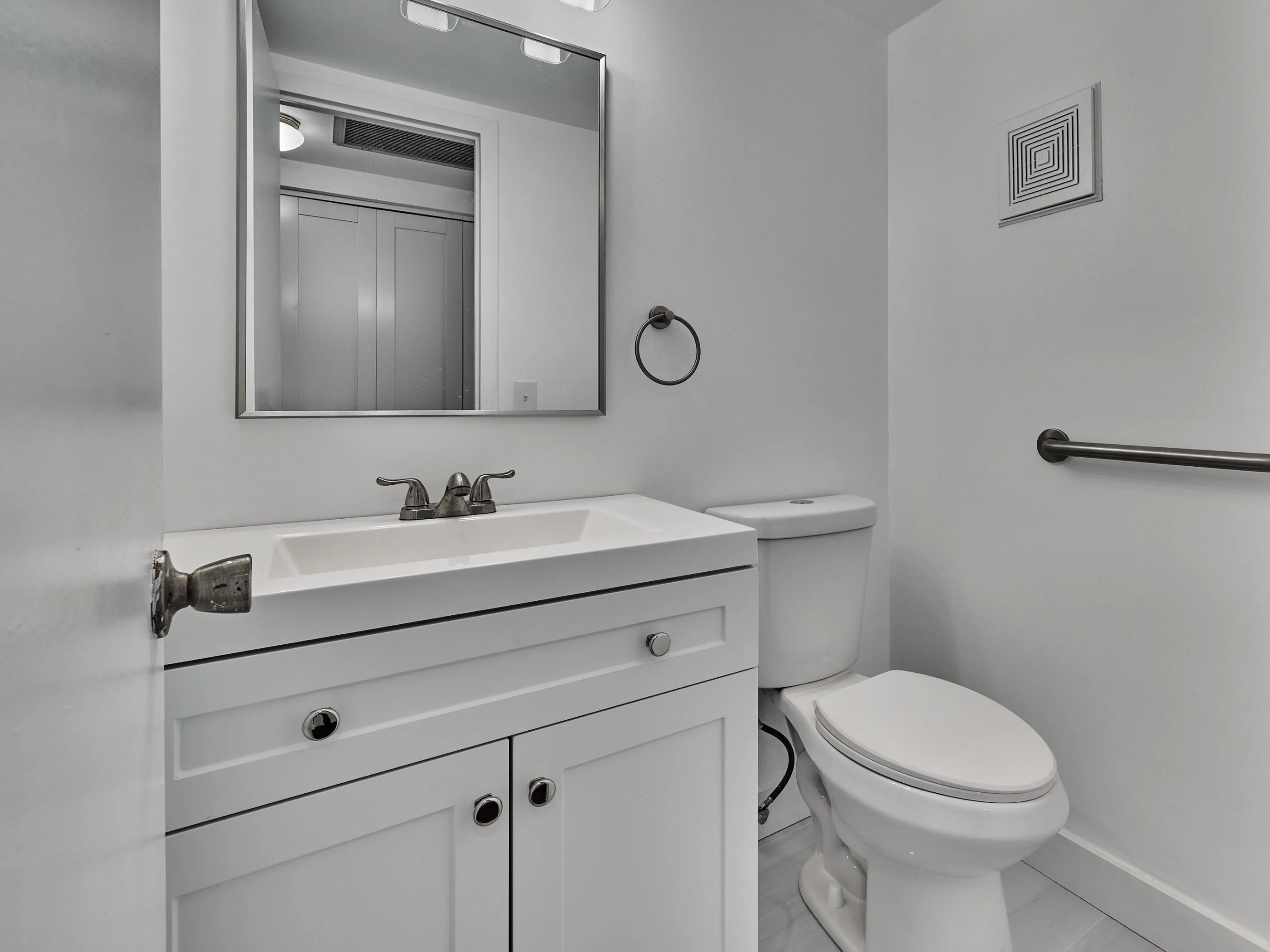 White vanity with shaker-style cabinetry, an integrated white sink, and a brushed nickel faucet