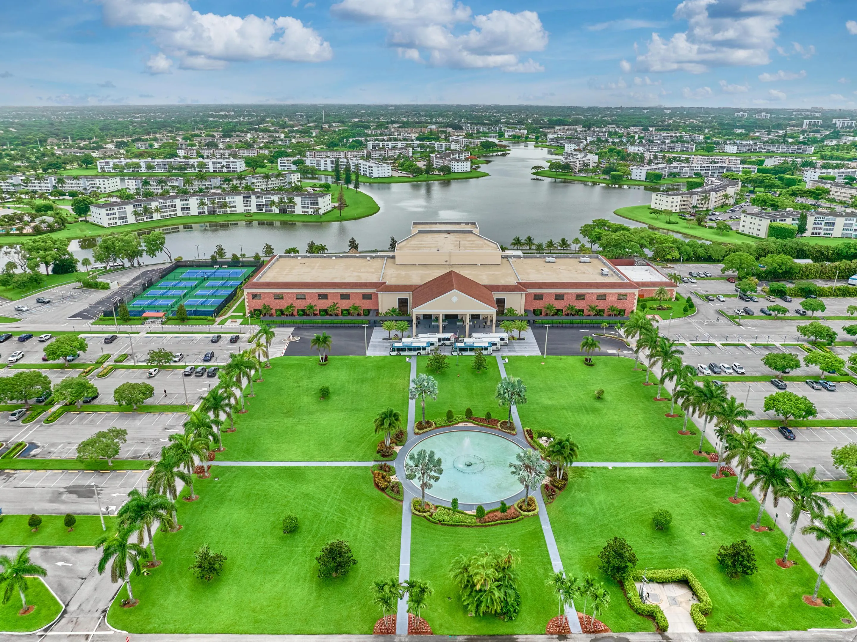Spacious facility featuring extensive green space, a central water feature, and large parking areas