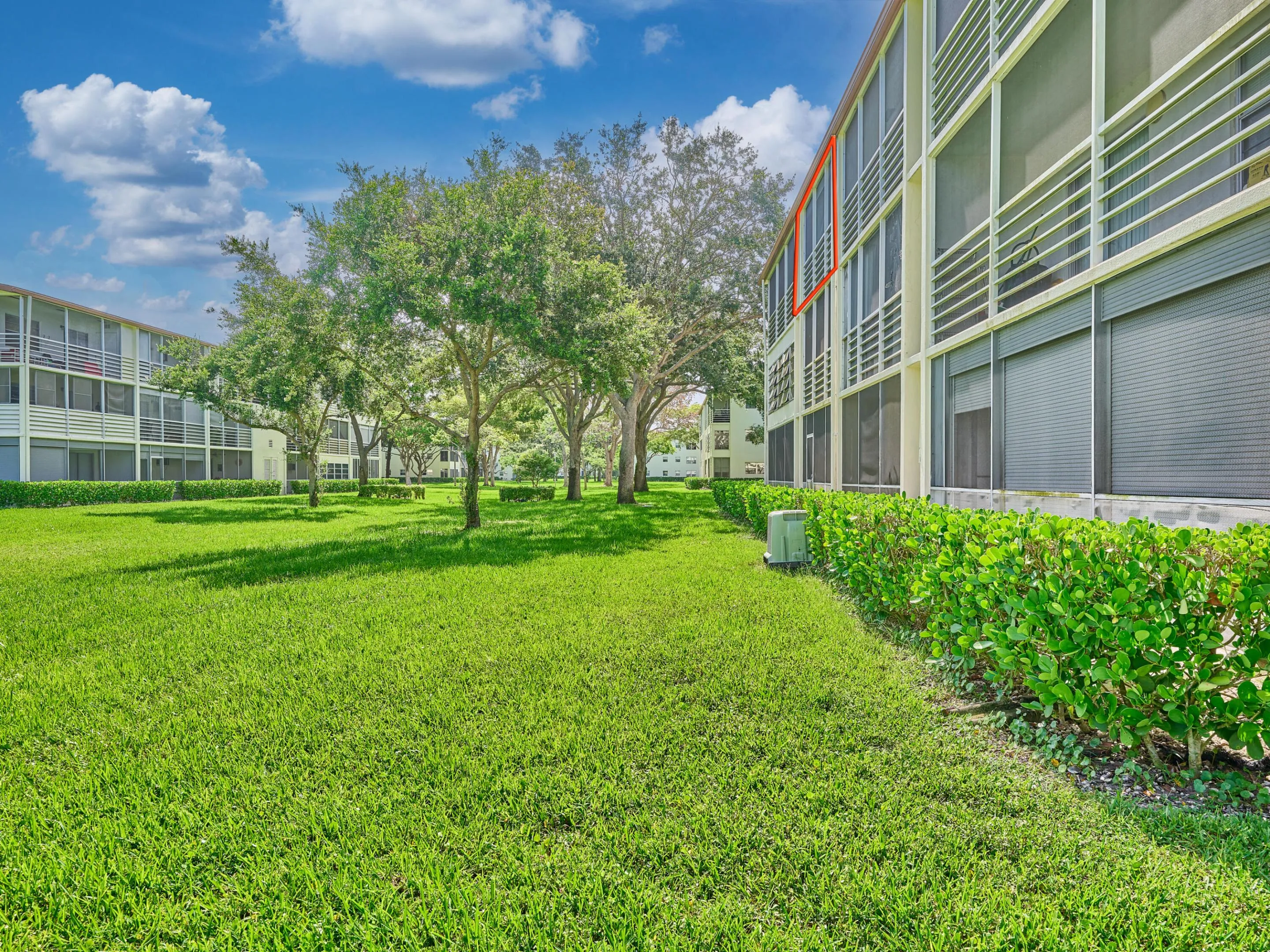 Lush green lawn with mature trees and manicured shrubbery bordering the building