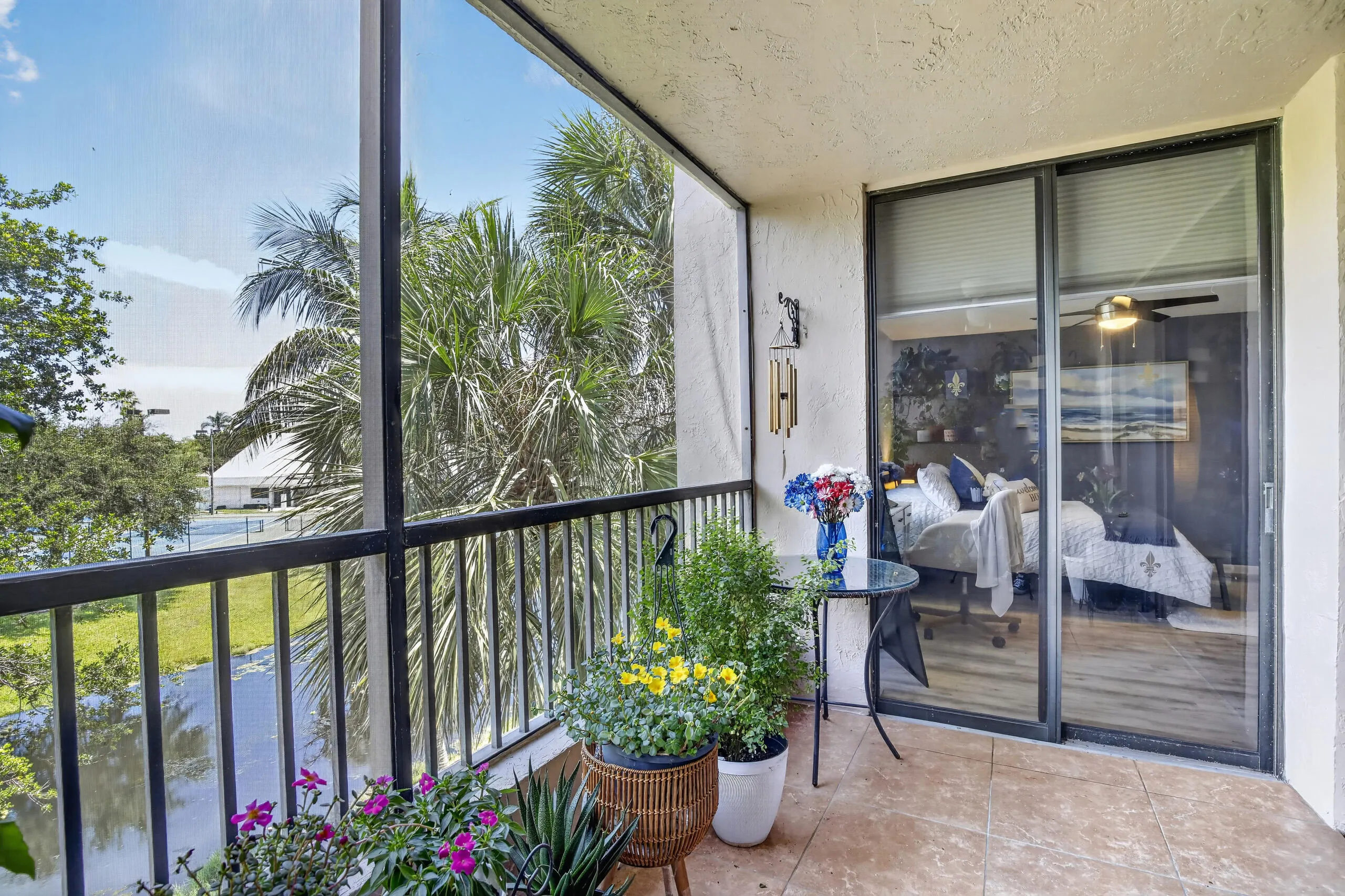 Screened balcony featuring textured tile flooring and a black metal railing