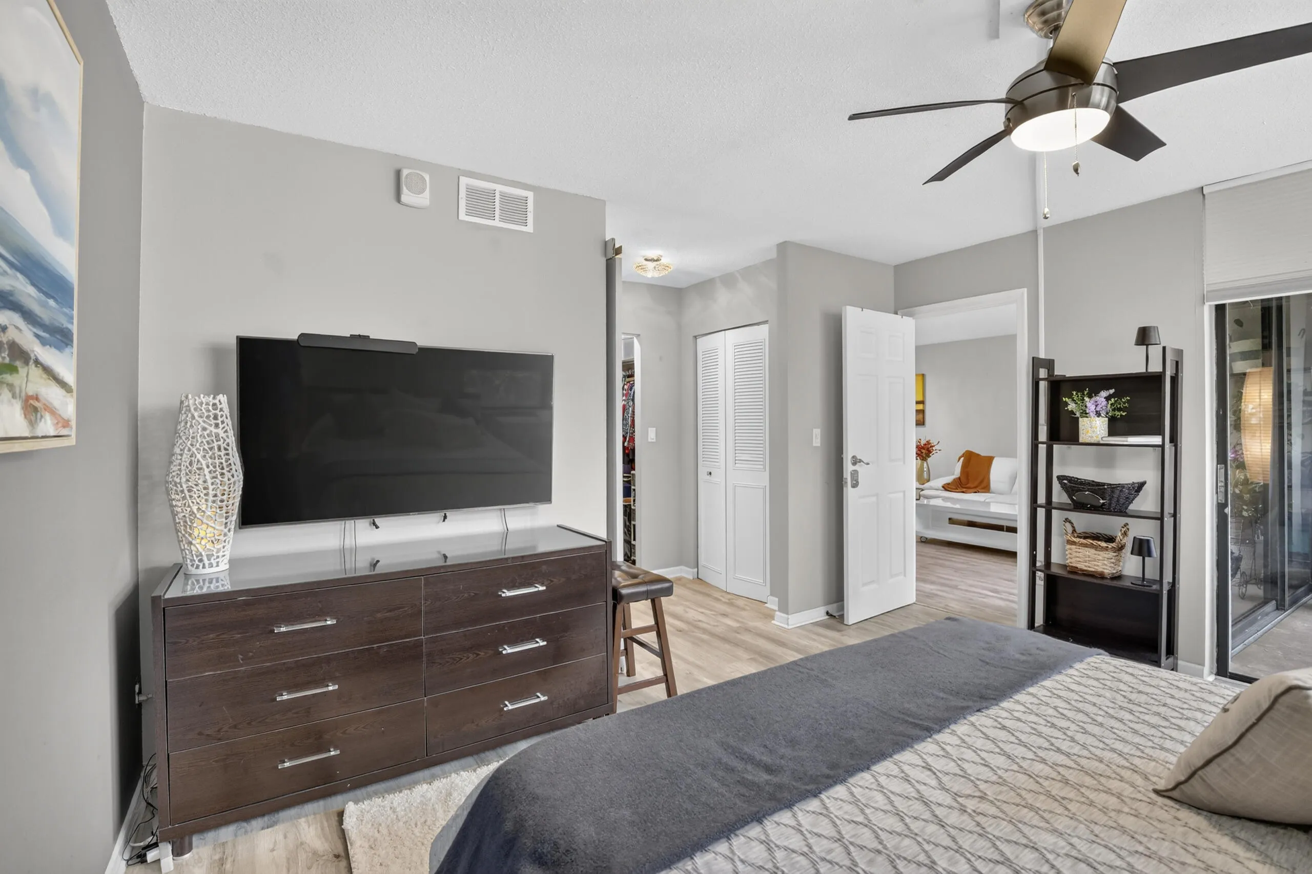 Spacious room featuring light wood-finish flooring, a ceiling fan, and a sliding glass door leading to exterior space