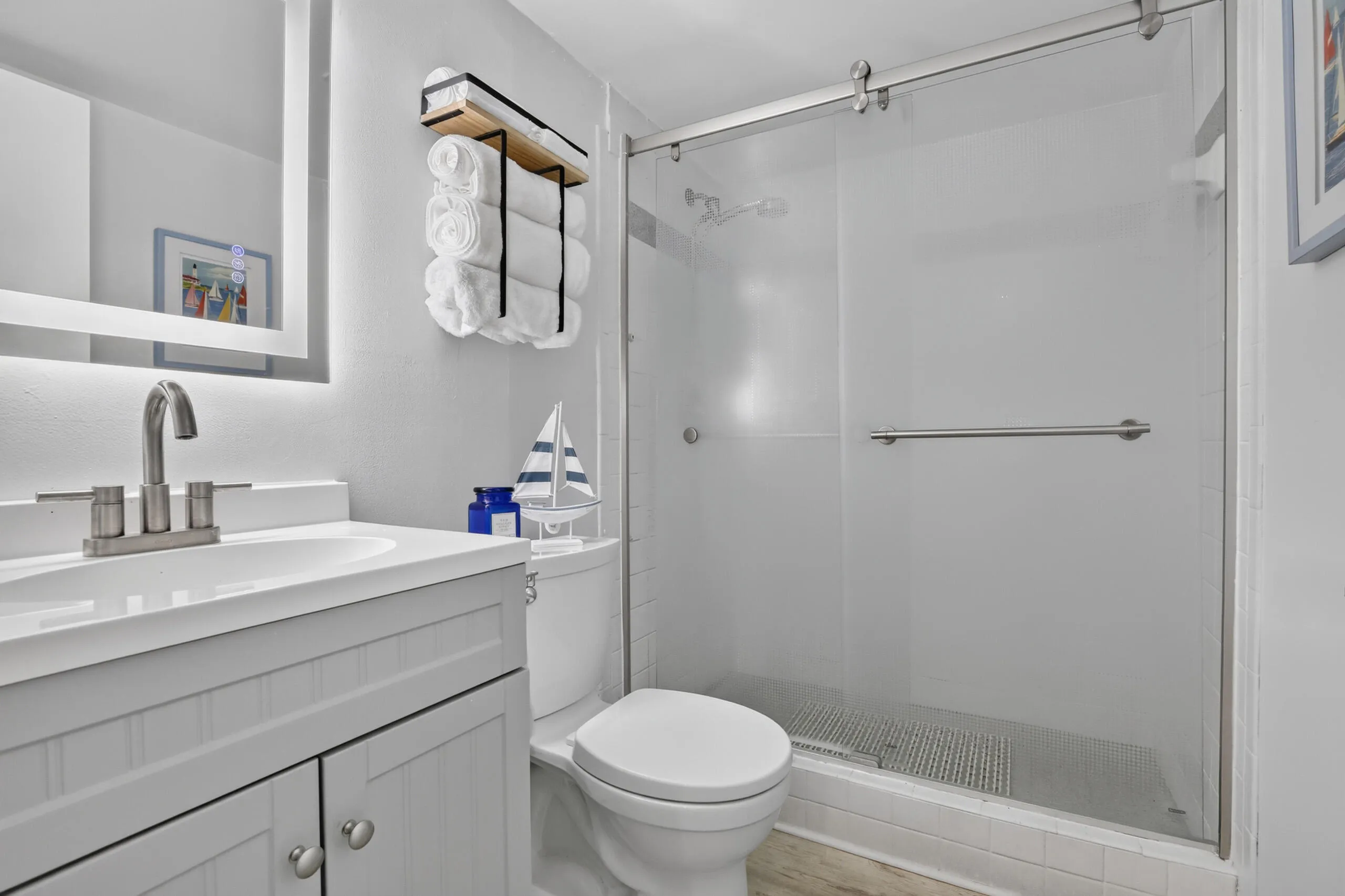 Contemporary bathroom featuring a single vanity with a white countertop, brushed nickel faucet, and a mirror with integrated lighting