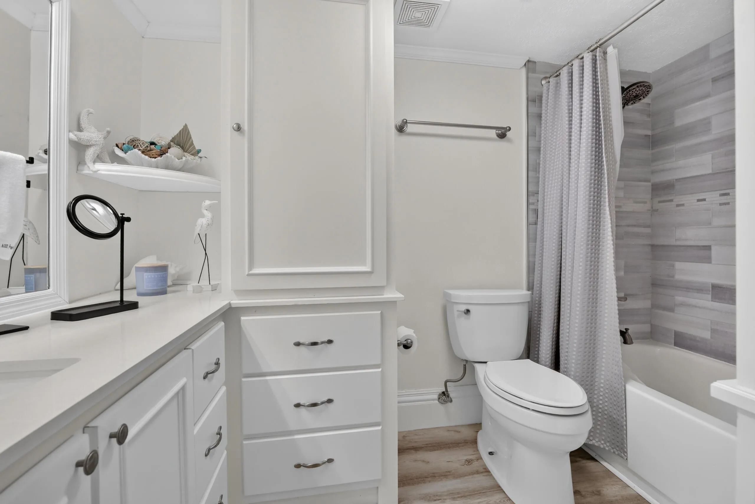 Full bathroom featuring a white vanity with integrated sink, a built-in storage cabinet, a toilet, a tub with a shower, and wood-finish flooring