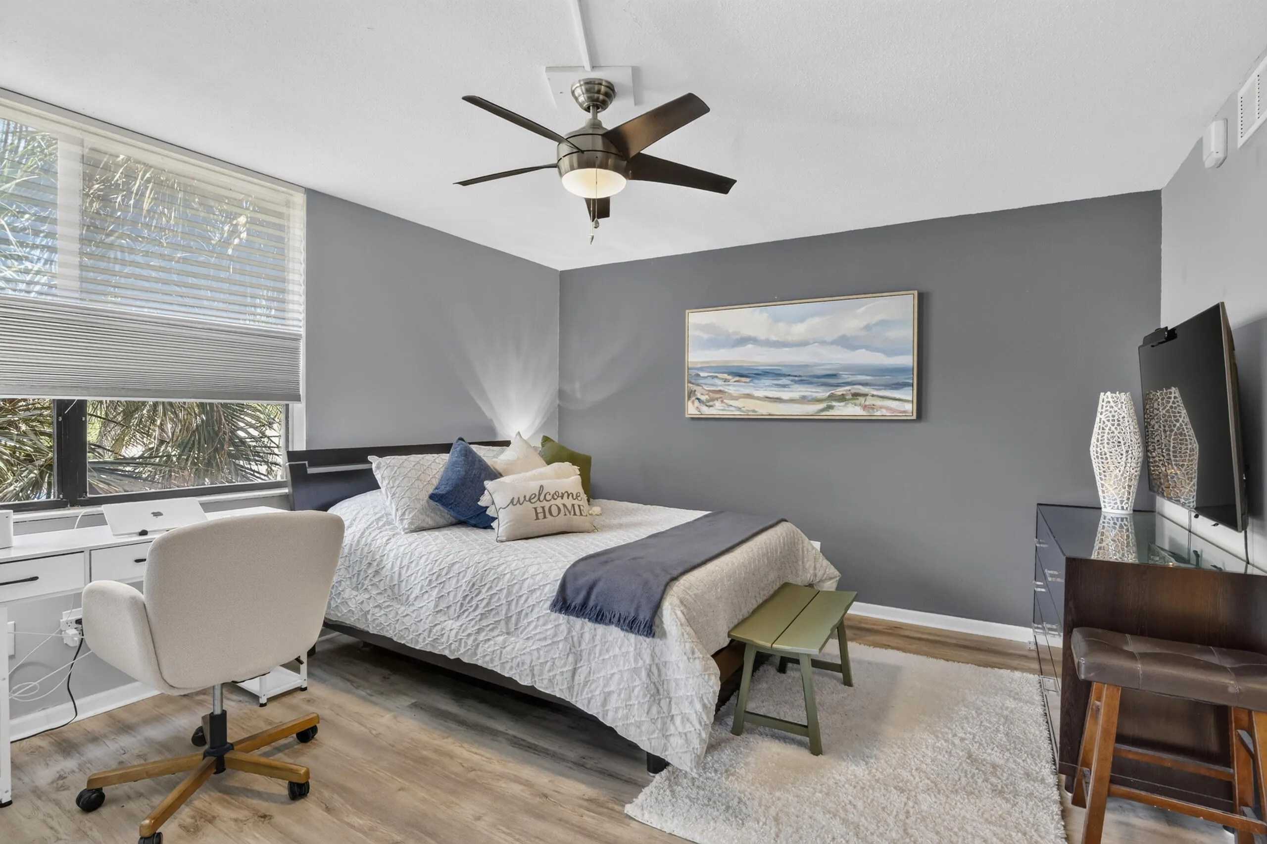 Bedroom with wood-finish flooring, a ceiling fan with integrated lighting, and a large window featuring horizontal blinds