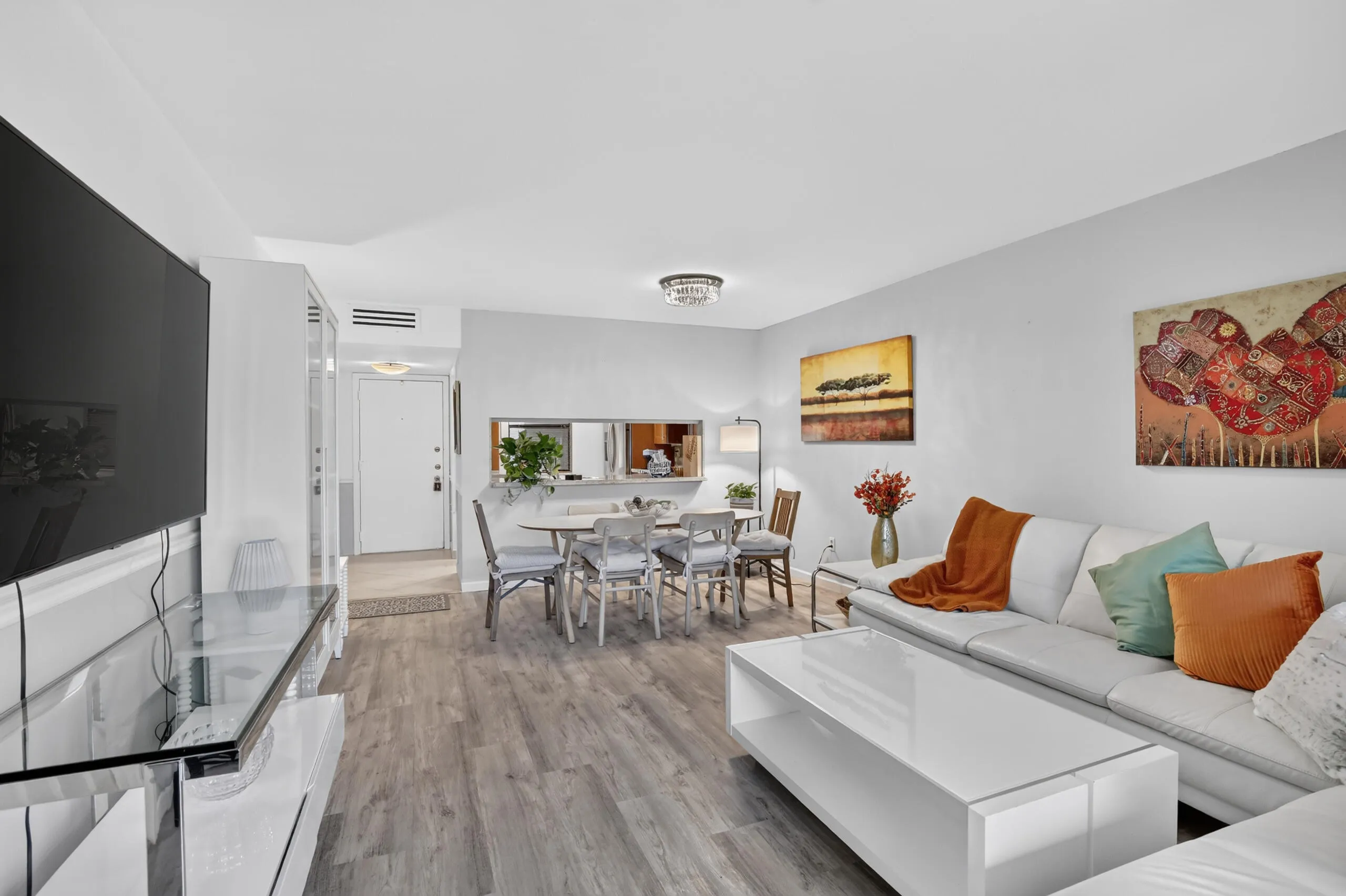 Open-concept living and dining area featuring wood-finish flooring, white walls, and a recessed ceiling light fixture