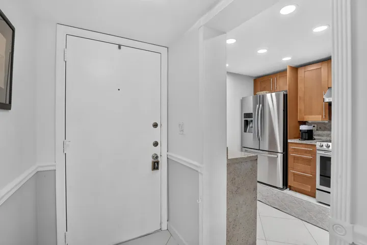 Entryway featuring a white door with multiple locks, chair rail molding, and tile flooring