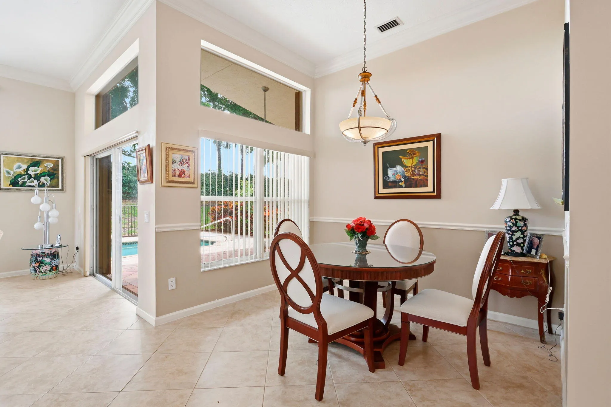 Dining area featuring tile flooring, high ceilings with crown molding, a transom window, and sliding glass doors providing outdoor access