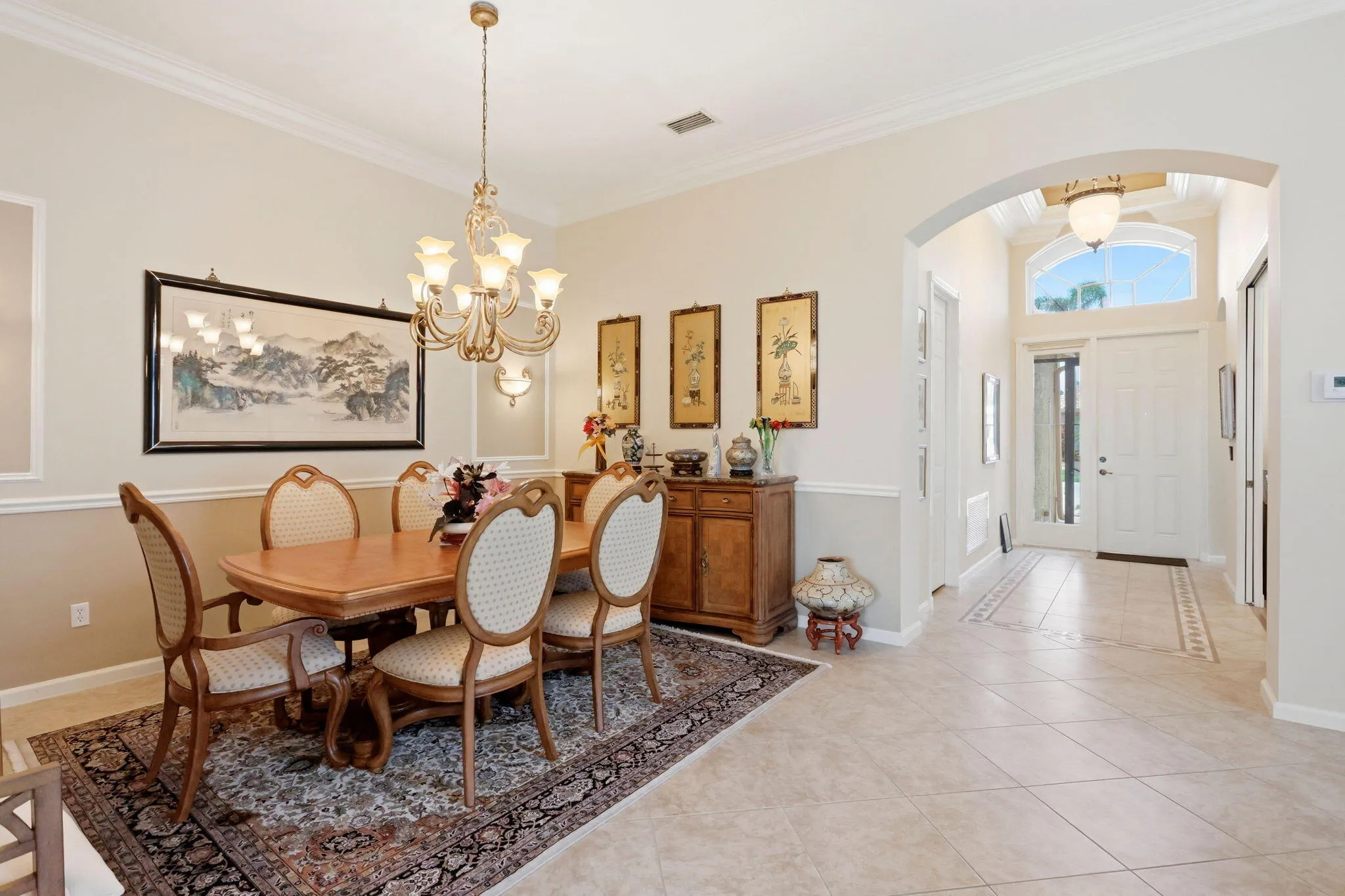 Dining area with crown molding and wainscoting, featuring a bronze-finish chandelier