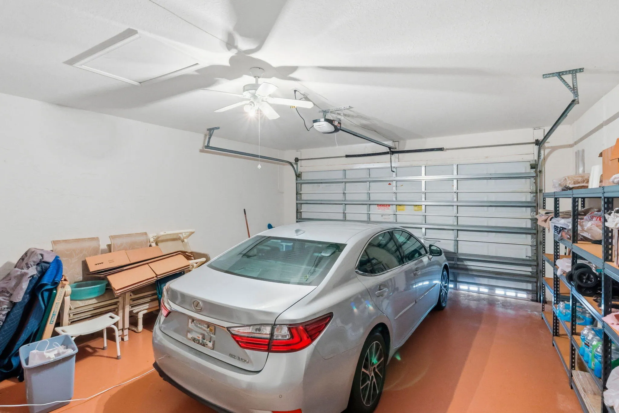 Spacious garage featuring a sectional garage door, automatic opener, ceiling fan, and access panel