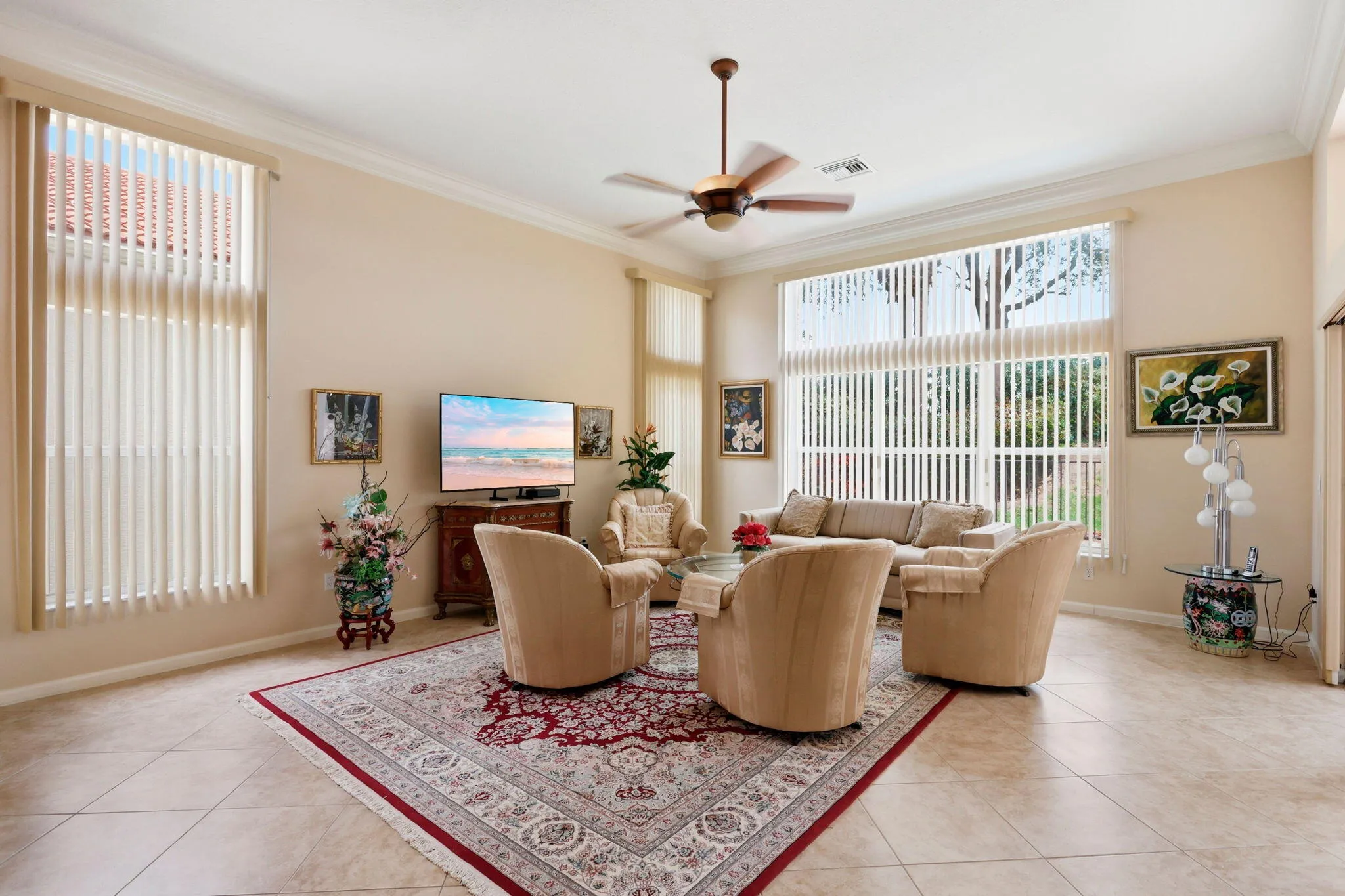 Spacious living area featuring high ceilings, crown molding, large window treatments, a ceiling fan, and ceramic tile flooring