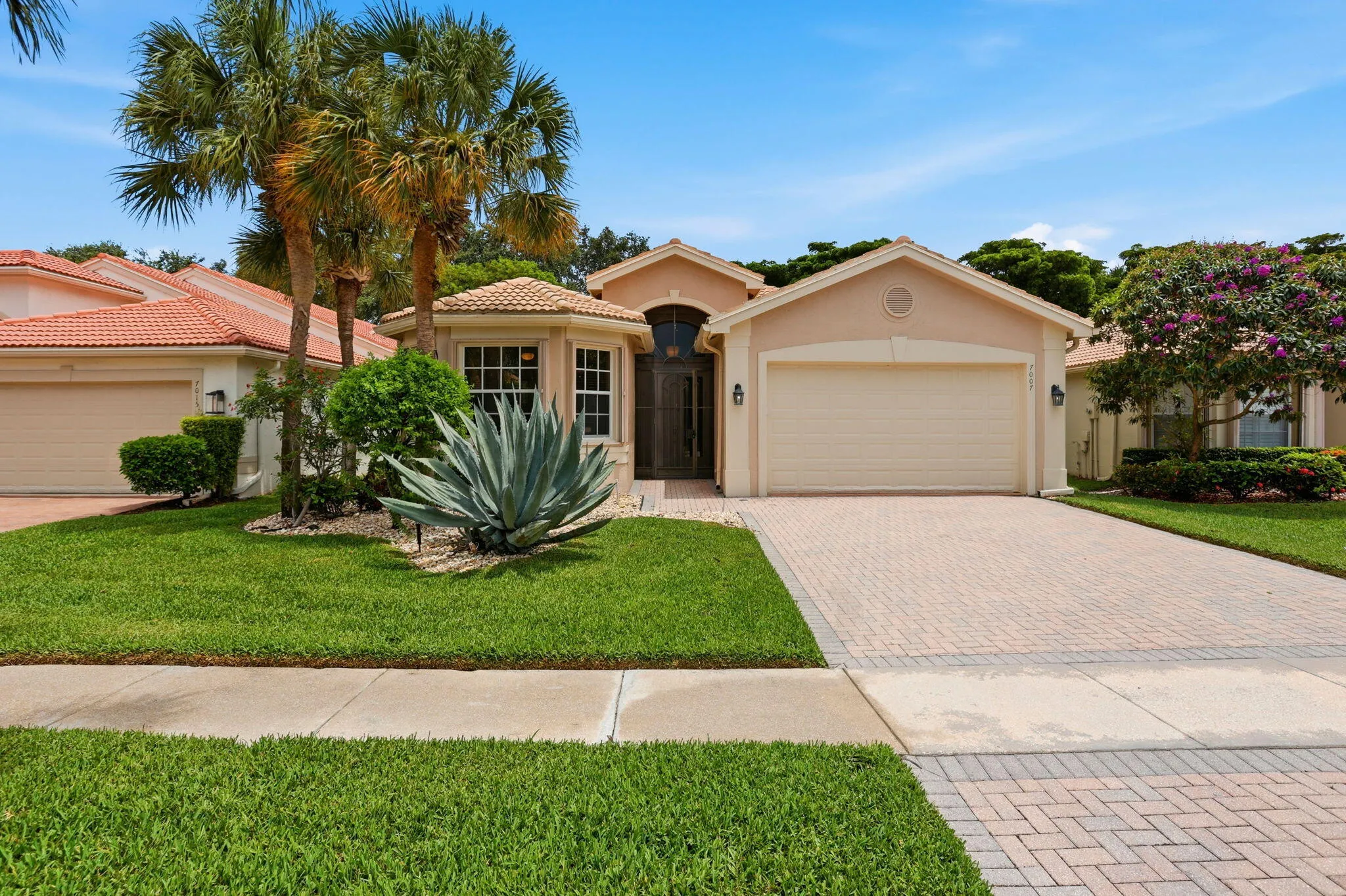 Front exterior with a paver driveway, an attached garage, and a tiled roofline