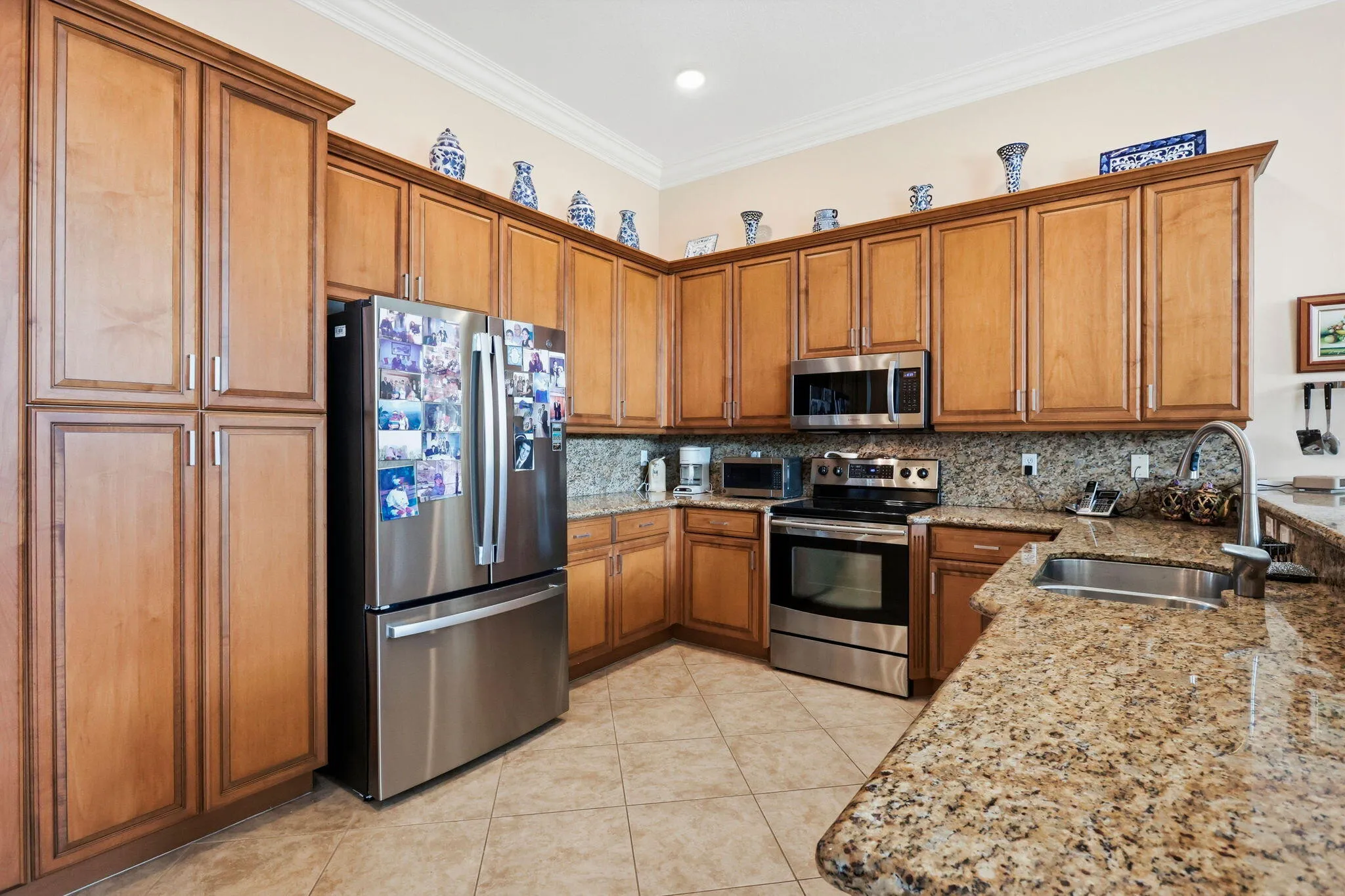Kitchen featuring light wood cabinetry, granite countertops, stainless steel appliances, and tiled flooring