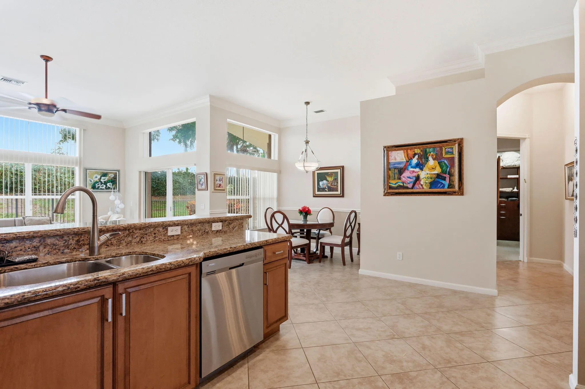 Kitchen island featuring a double basin sink, gooseneck faucet, stainless steel dishwasher, and a mottled countertop