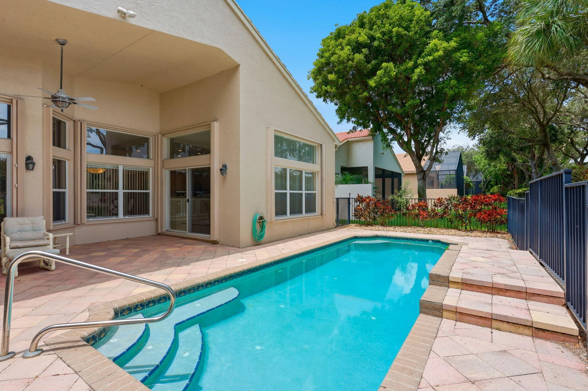 Outdoor swimming pool featuring integrated steps and a metal handrail