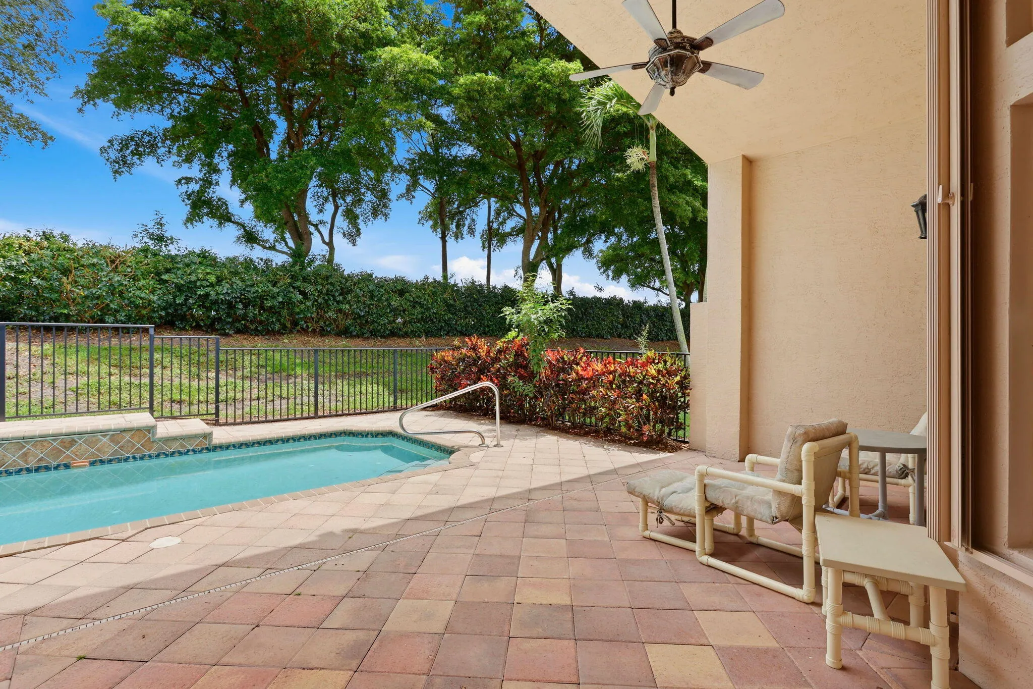 Covered patio featuring a ceiling fan, paver flooring, and a fenced pool with a tiled edge