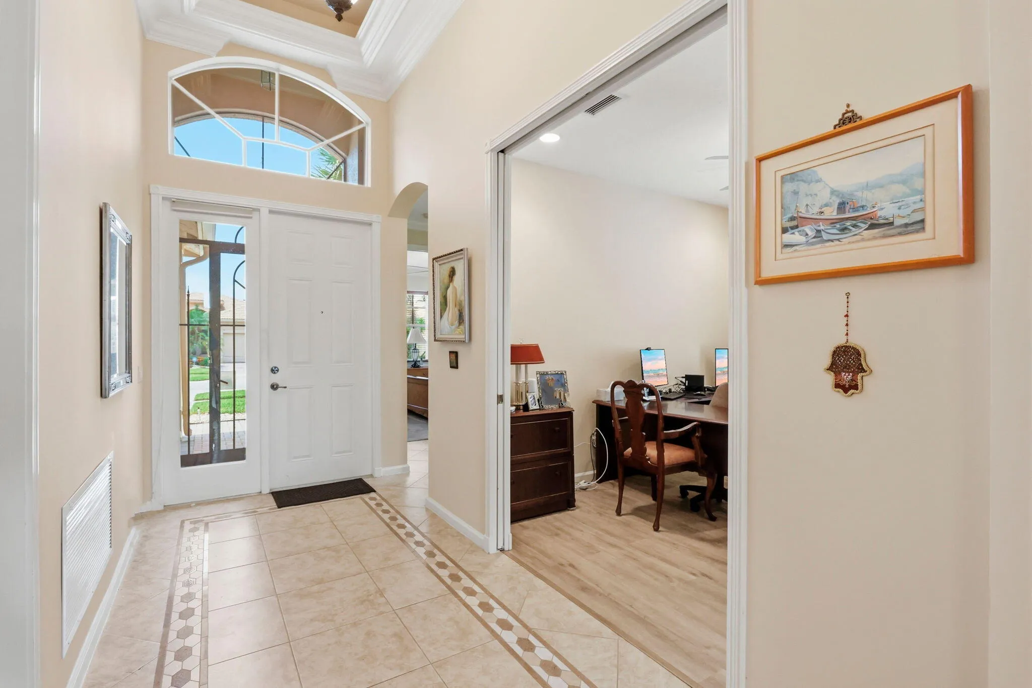 Inviting entryway featuring a white paneled front door with a sidelight, an arched transom window, and a coffered ceiling