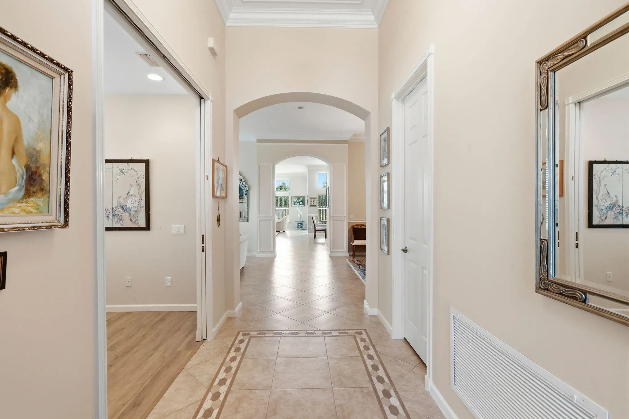 Tiled entryway featuring an intricate tile border, archway, crown molding, and recessed lighting