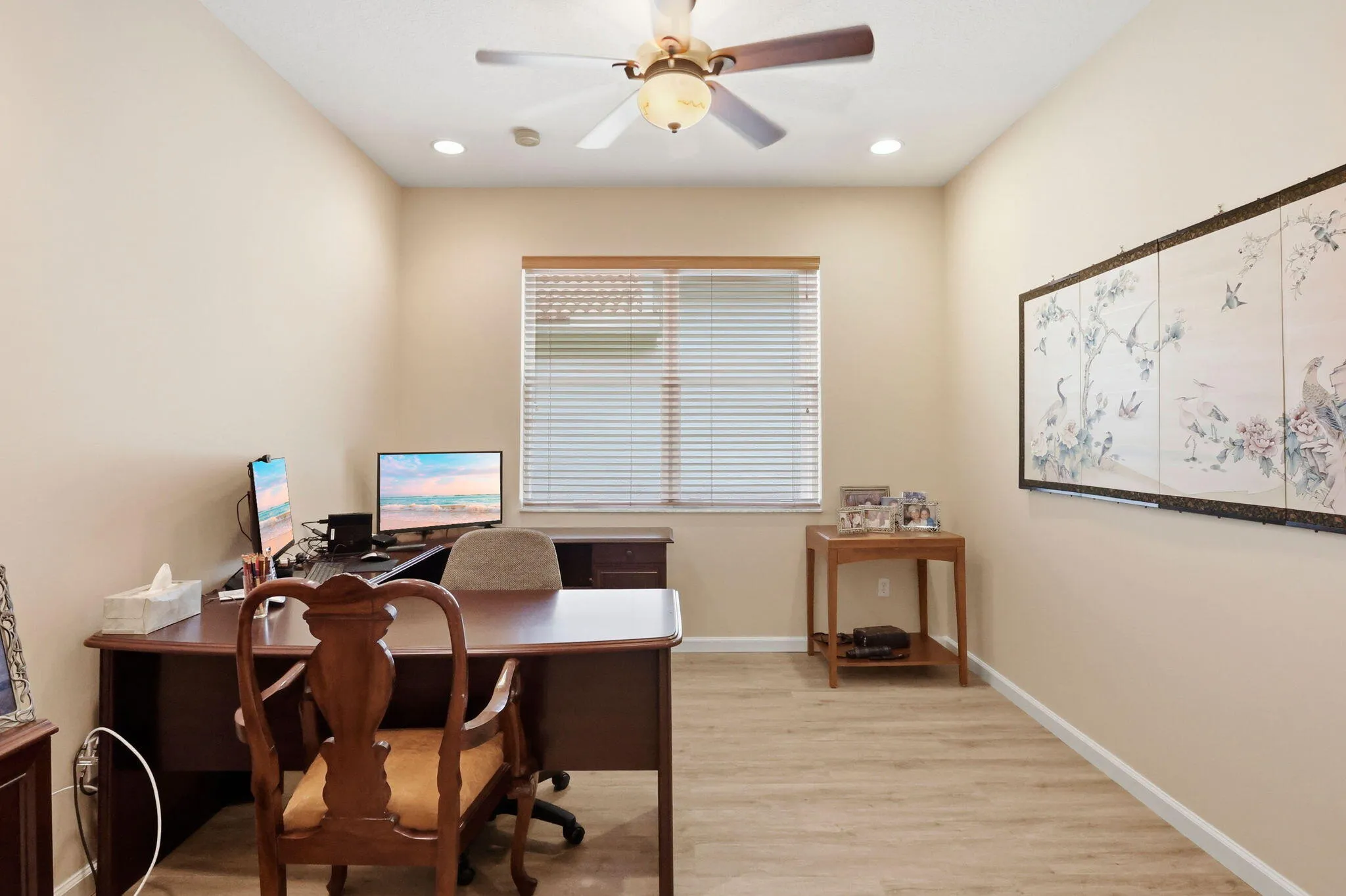 Neutral-toned interior room featuring wood-finish flooring and a single window with horizontal blinds