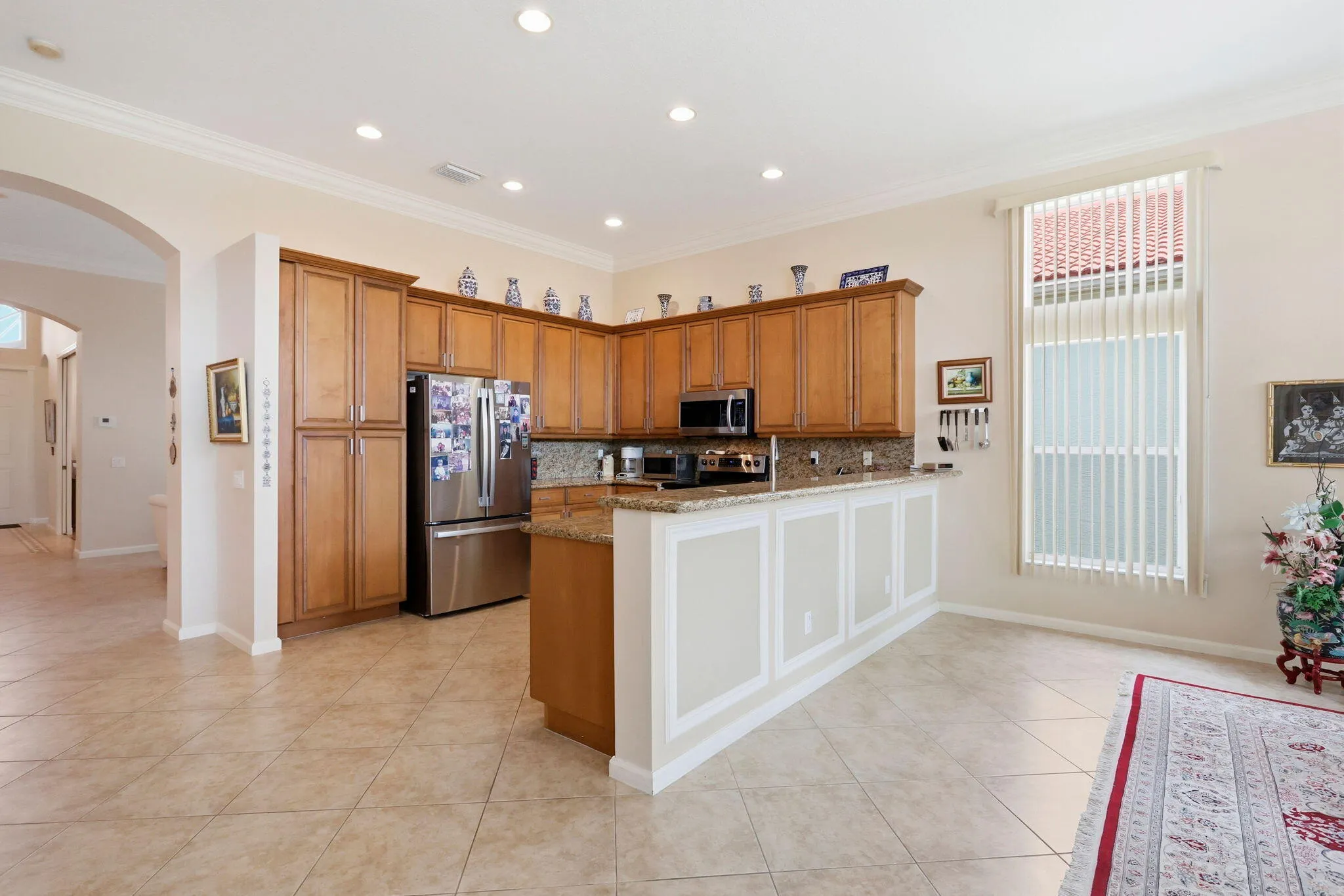 Kitchen featuring wood cabinetry, stainless steel appliances, granite countertops, and tiled flooring
