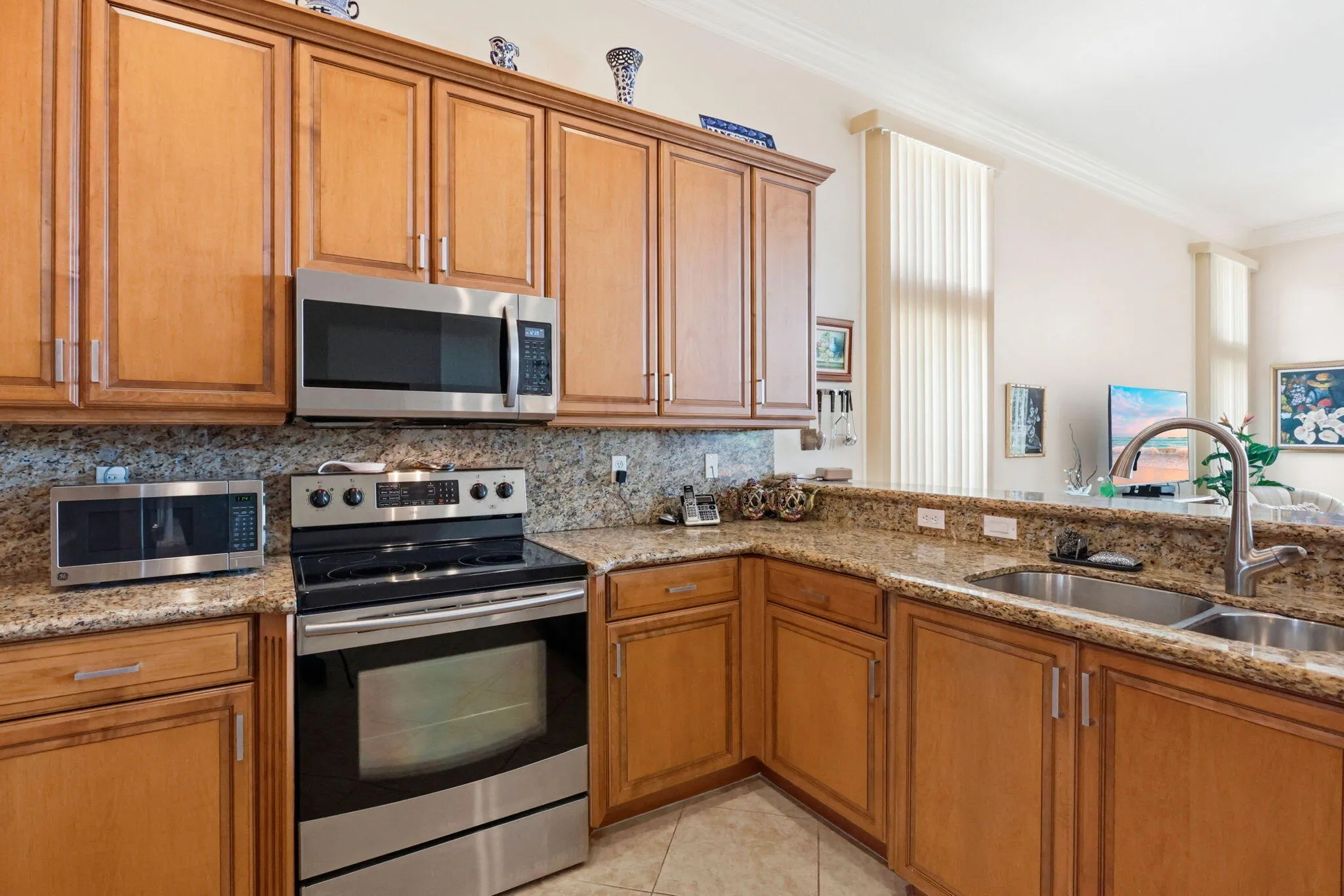Kitchen featuring wood cabinetry, granite countertops, stainless steel appliances, and a double basin sink