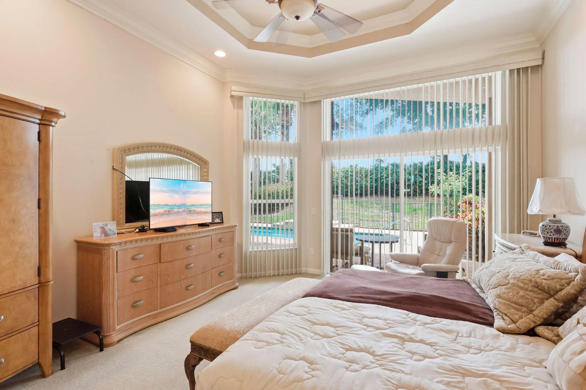 Recessed ceiling with a central fan, crown molding, and large bay windows