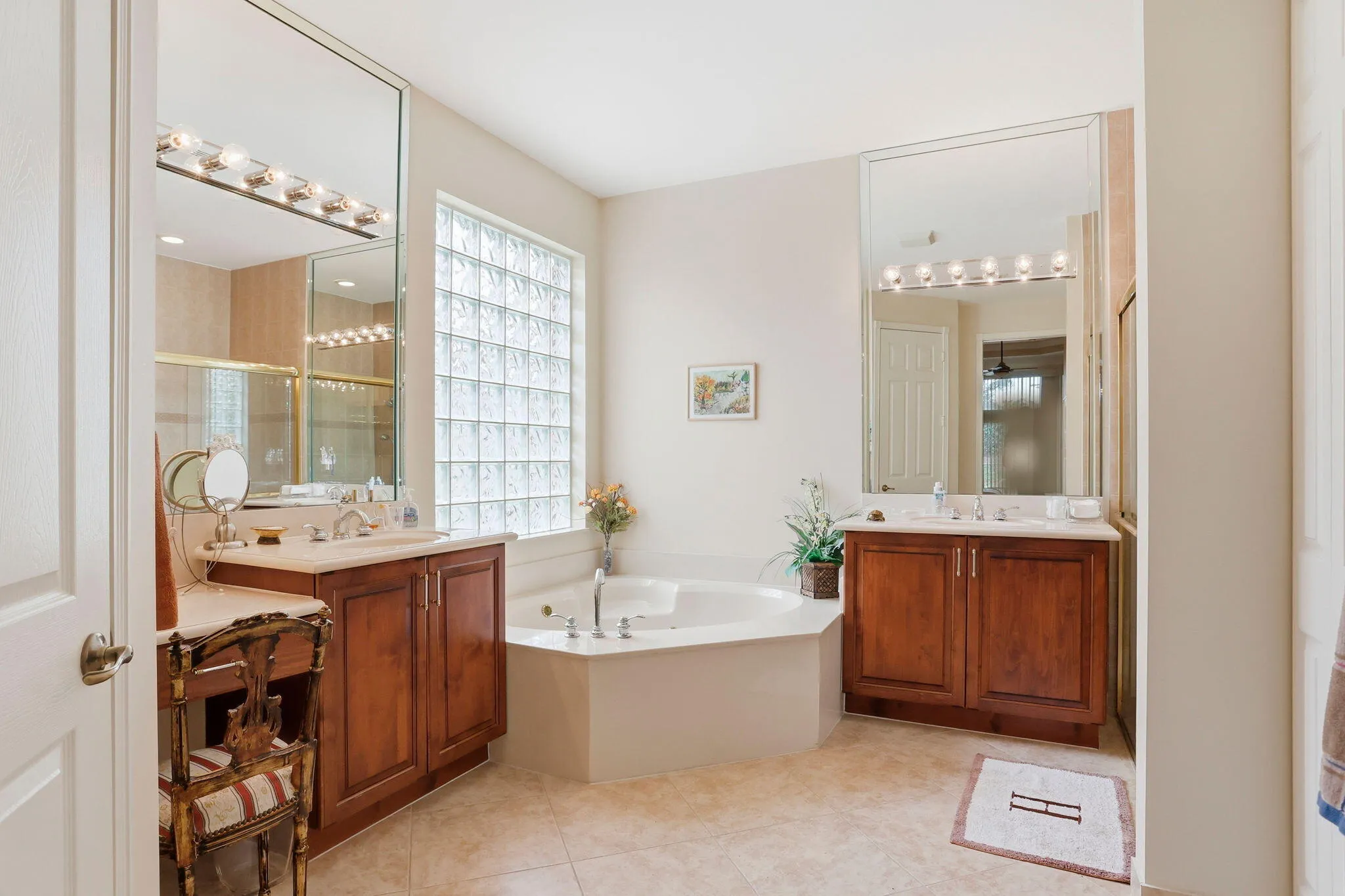 Corner garden tub with deck-mounted fixtures, set under a large glass block window