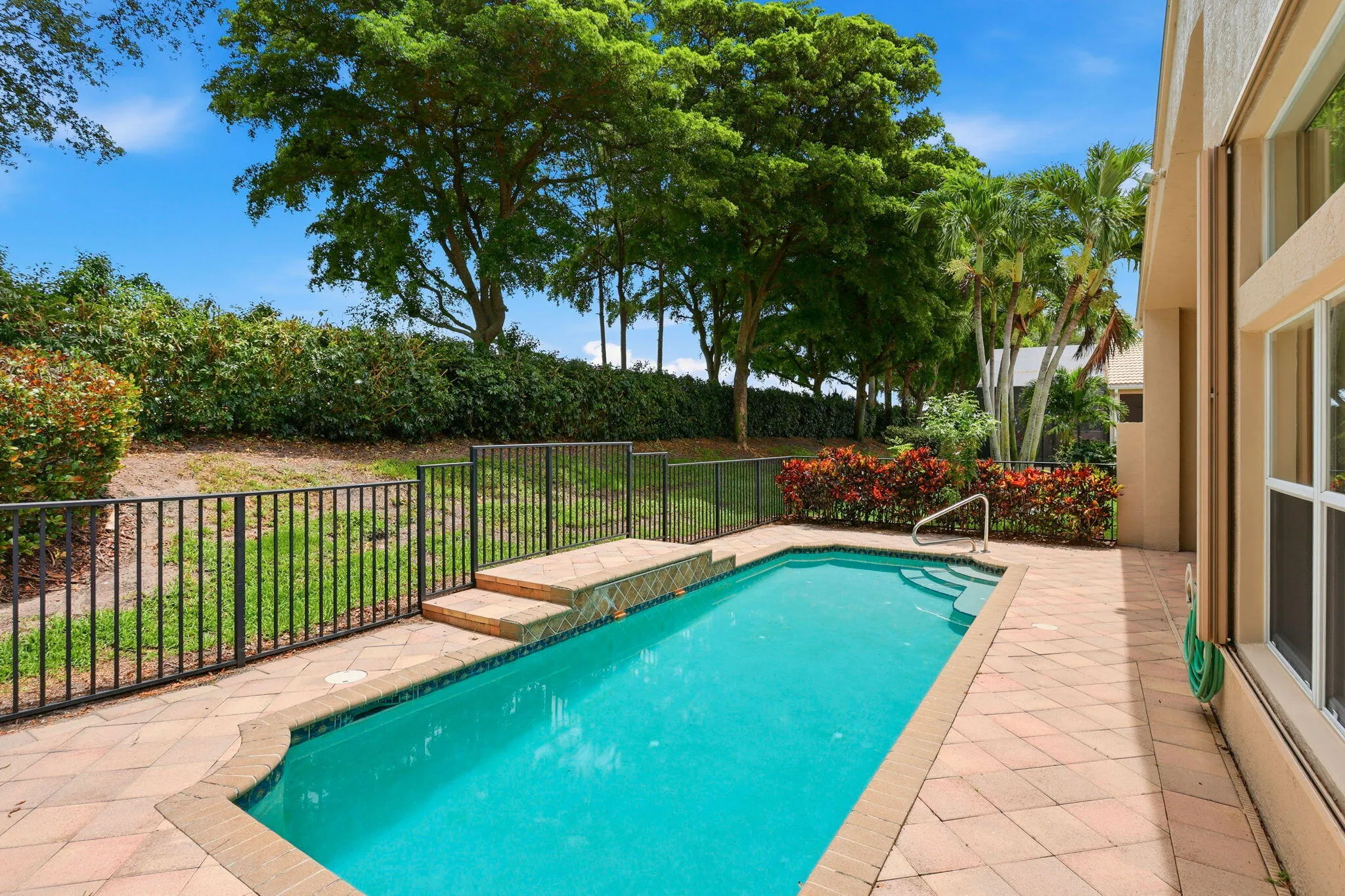Rectangular swimming pool featuring a tiled spa entry, integrated steps, and a metal handrail