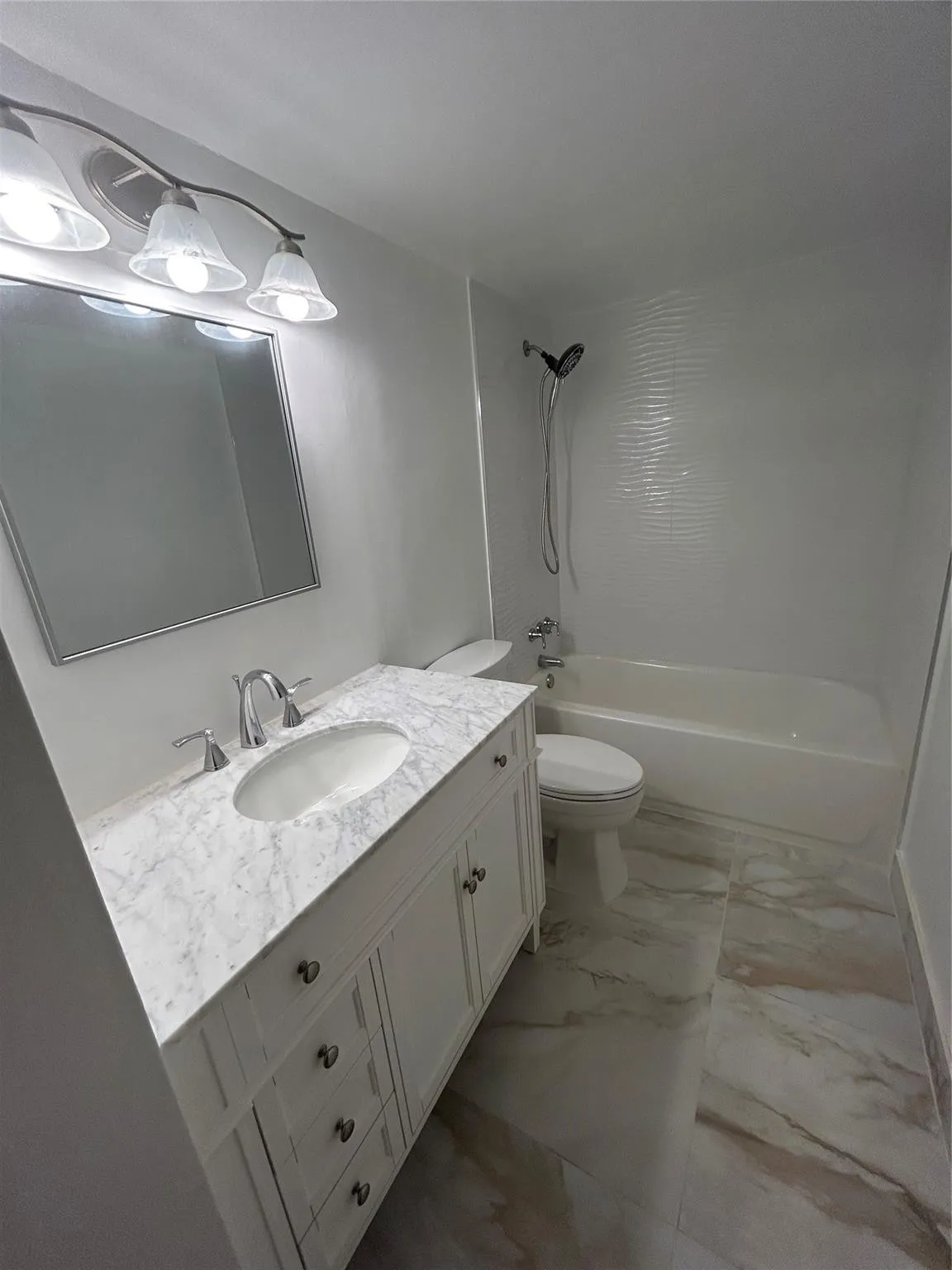 New vanity has marble top and steel faucet and knobs. three draws are vertical and two doors open below the porcelain sink. Mirror above is length of vanity and has a steel frame. New Light fixture has three globe horizontal glass covering connected to a dimmer switch. there is a heat lamp on the ceiling. Bathtub is new with steel facuet and knobs. New Shower hose handle is attached to a hanger with adjustable speeds. New toilet is between the vanity and the tub. Storage closet prehung door.