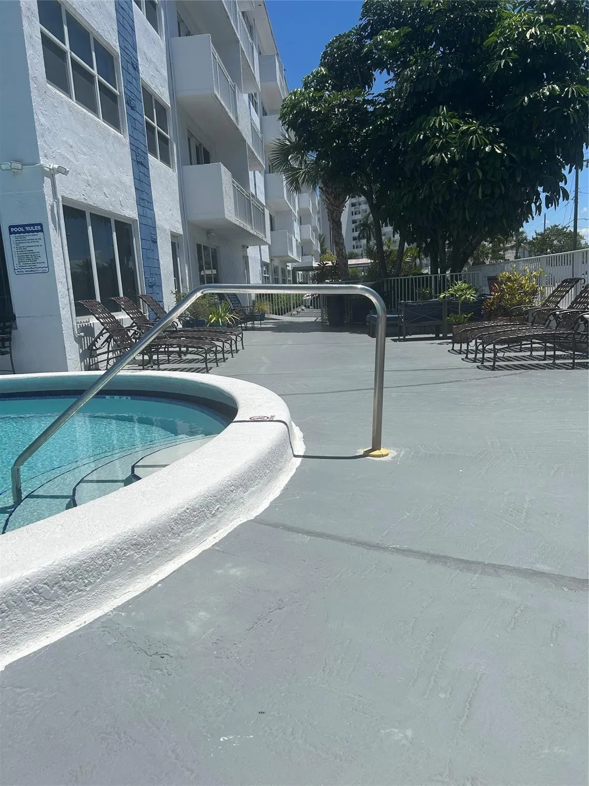 outdoor area is fenced and has heated pool with steps and railing, lounge chairs, shower