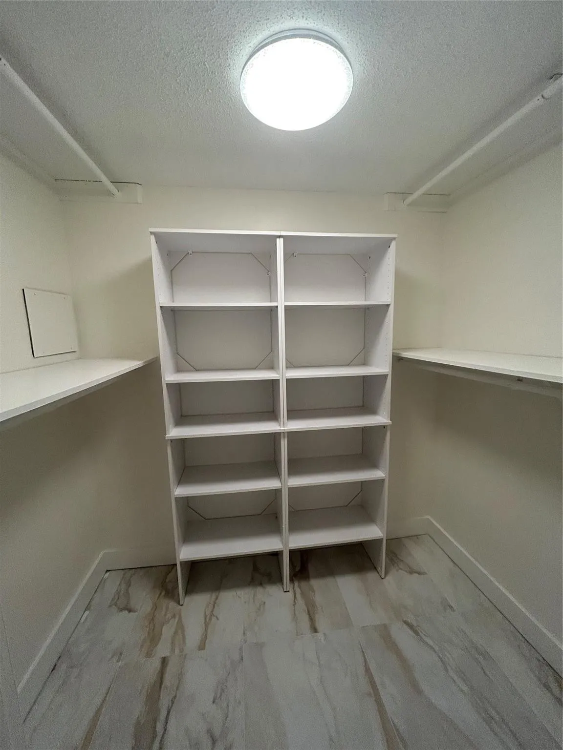 Walk in closet has crystal light fixture with remote control or wall switch, four hanging rods, two closet length size shelves, ten smaller shelves. Ceramic tile flooring,new baseboard and paint