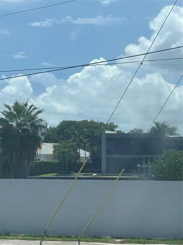 from windows are intracoastal waterway homes with greenery trees. A fence now stands infront of intracoastal view of water and boats going by can be seen above