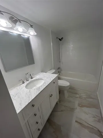 New vanity has marble top and steel faucet and knobs. three draws are vertical and two doors open below the porcelain sink. Mirror above is length of vanity and has a steel frame. New Light fixture has three globe horizontal glass covering connected to a dimmer switch. there is a heat lamp on the ceiling. Bathtub is new with steel facuet and knobs. New Shower hose handle is attached to a hanger with adjustable speeds. New toilet is between the vanity and the tub. Storage closet prehung door.