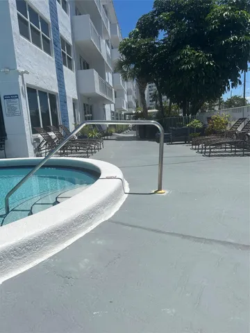 outdoor area is fenced and has heated pool with steps and railing, lounge chairs, shower