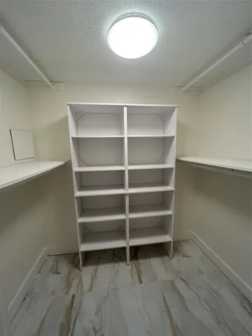 Walk in closet has crystal light fixture with remote control or wall switch, four hanging rods, two closet length size shelves, ten smaller shelves. Ceramic tile flooring,new baseboard and paint