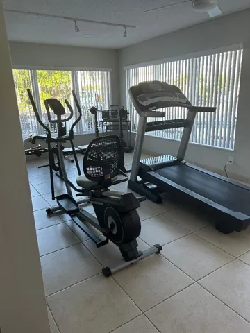 gym area in rec room has full length windows, audio system, ceiling lighting n fans, centeral ac, equipment for exercise